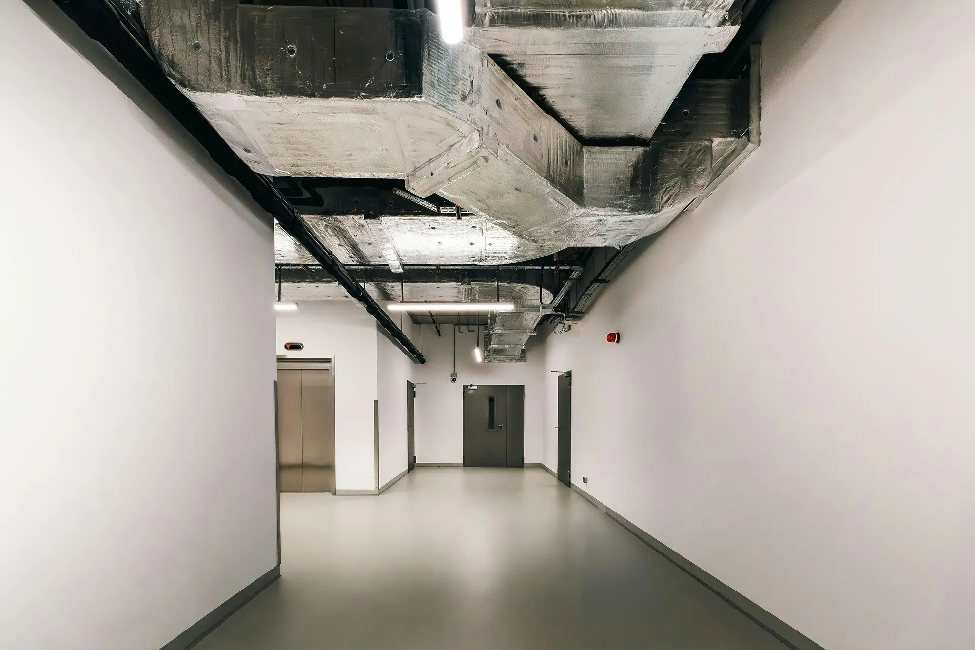 Finished corridor with lagged ductwork, cable tray and linear lighting exposed overhead
