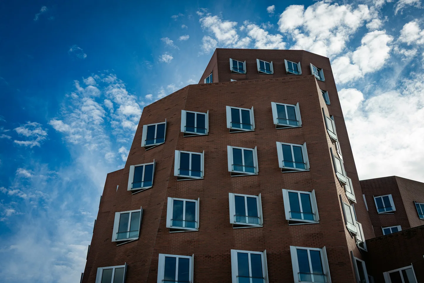 Contemporary brick commercial building with angled bay windows against a bright blue sky, Duesseldorf