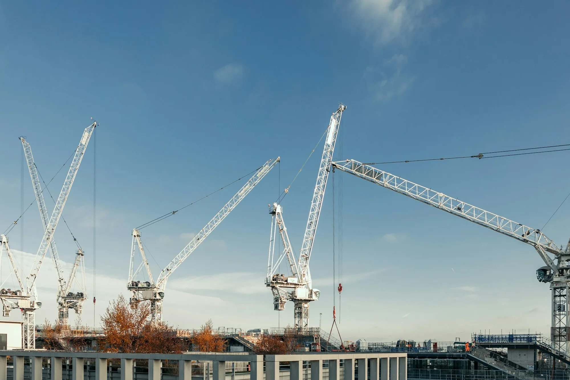 Tower cranes over a London construction site against a blue sky
