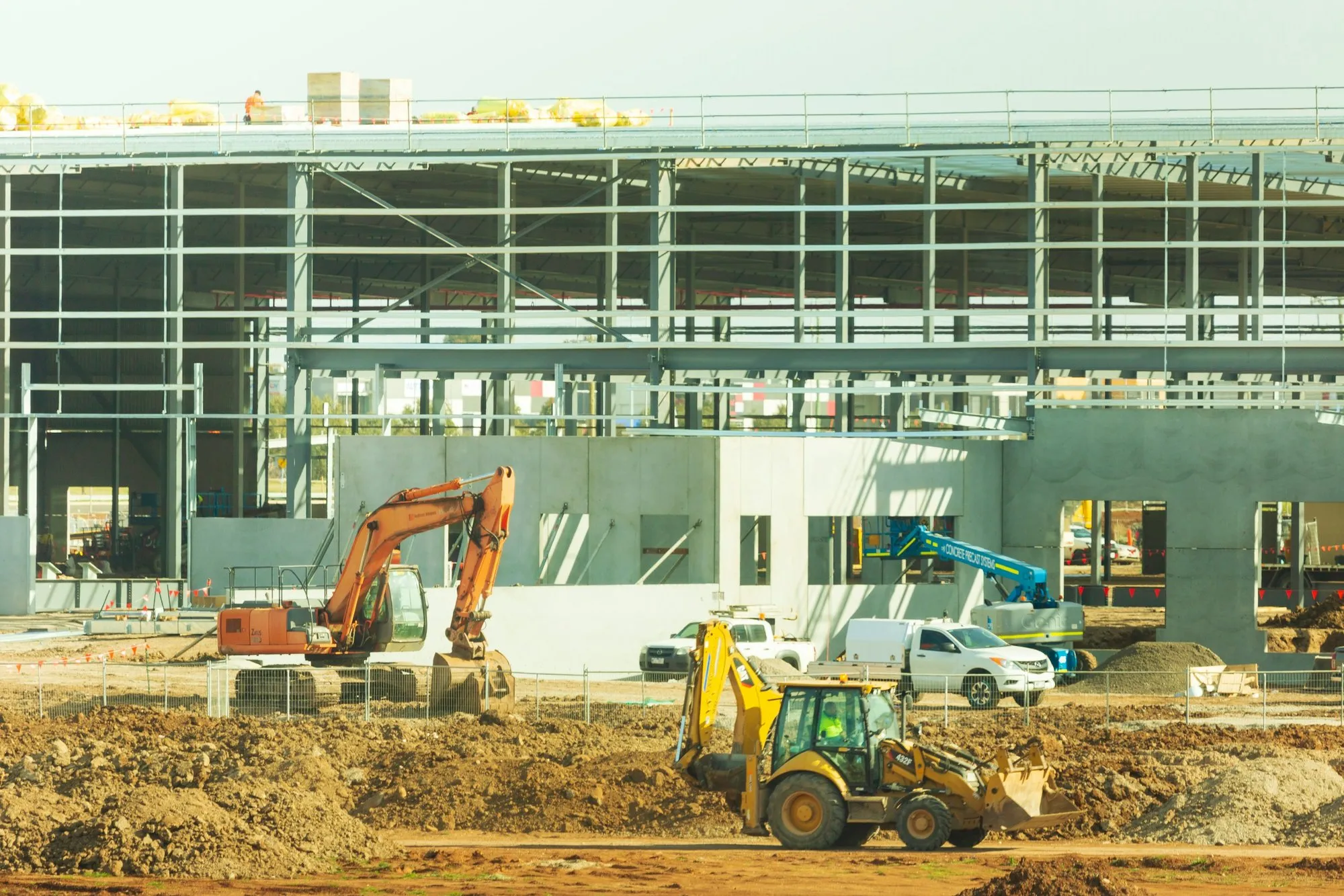 Excavators working beside a new commercial building frame