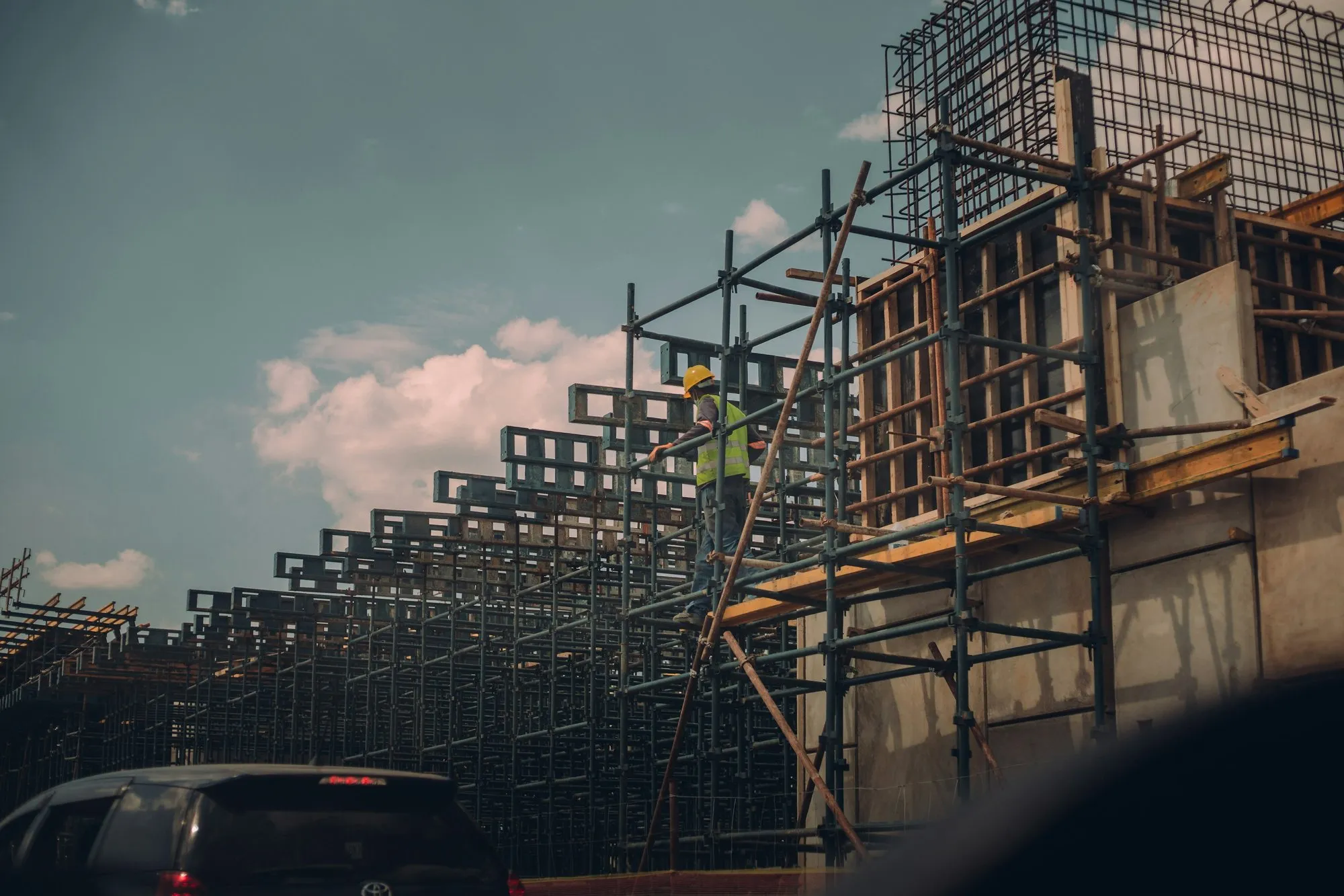 Site operative on scaffolding beside a new concrete frame