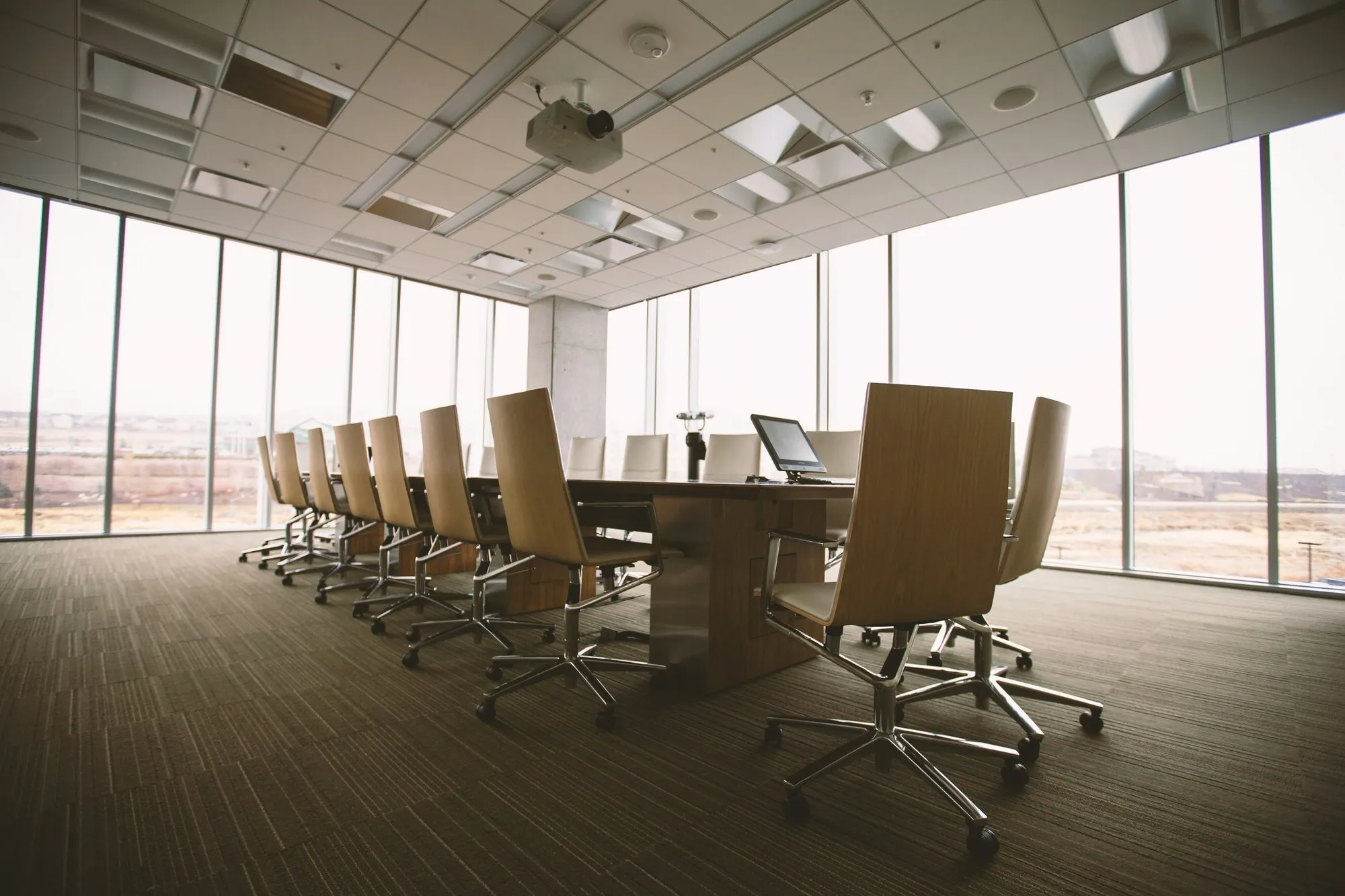 Large boardroom with a long table and chairs beside floor-to-ceiling windows