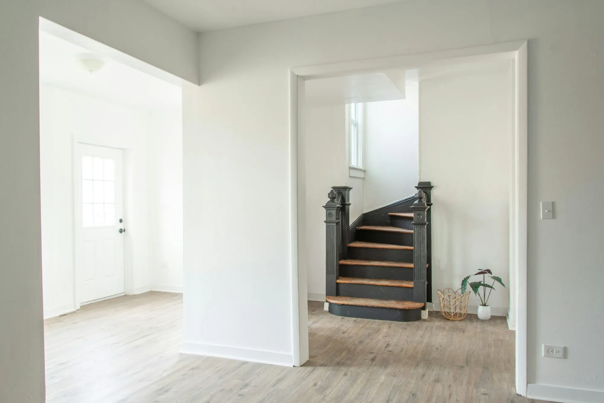 Finished white hallway with a dark timber staircase and new oak flooring