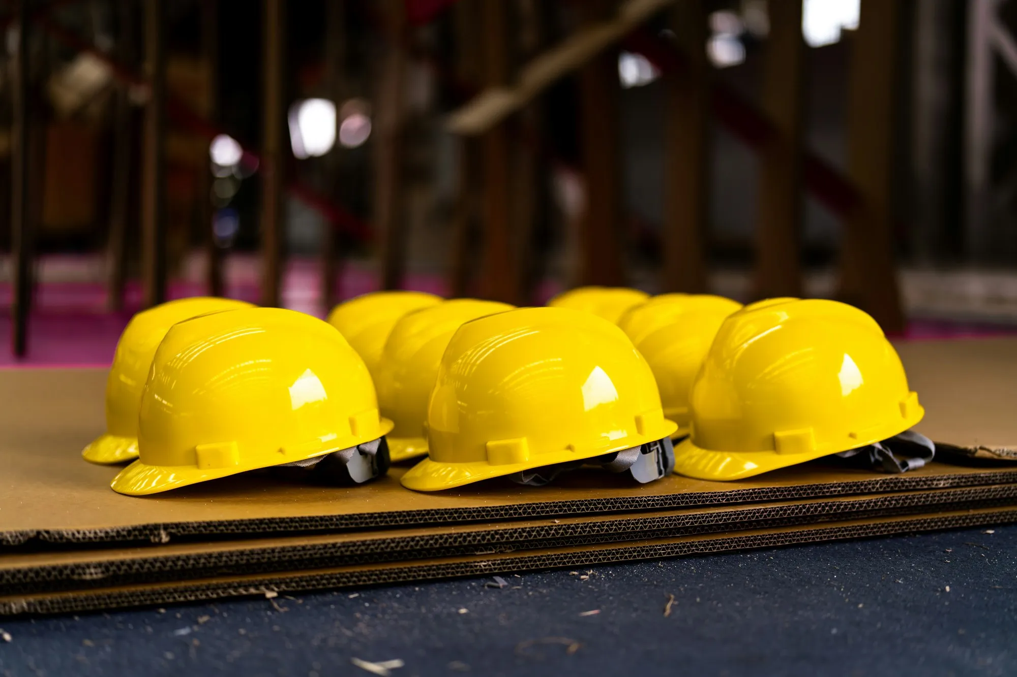 Row of bright yellow hard hats lined up on a site work surface