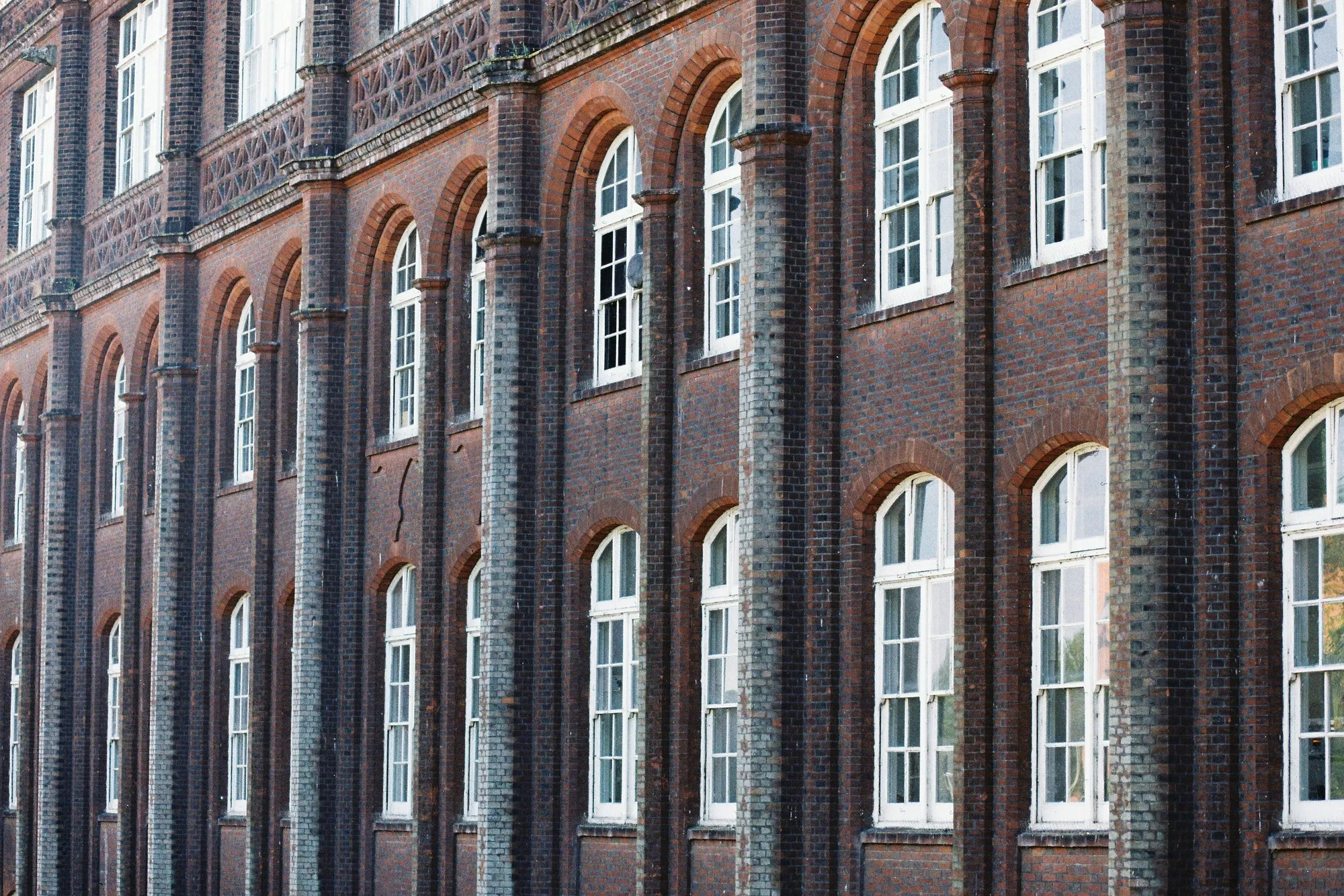 Victorian red brick facade with tall arched white windows, conversion candidate