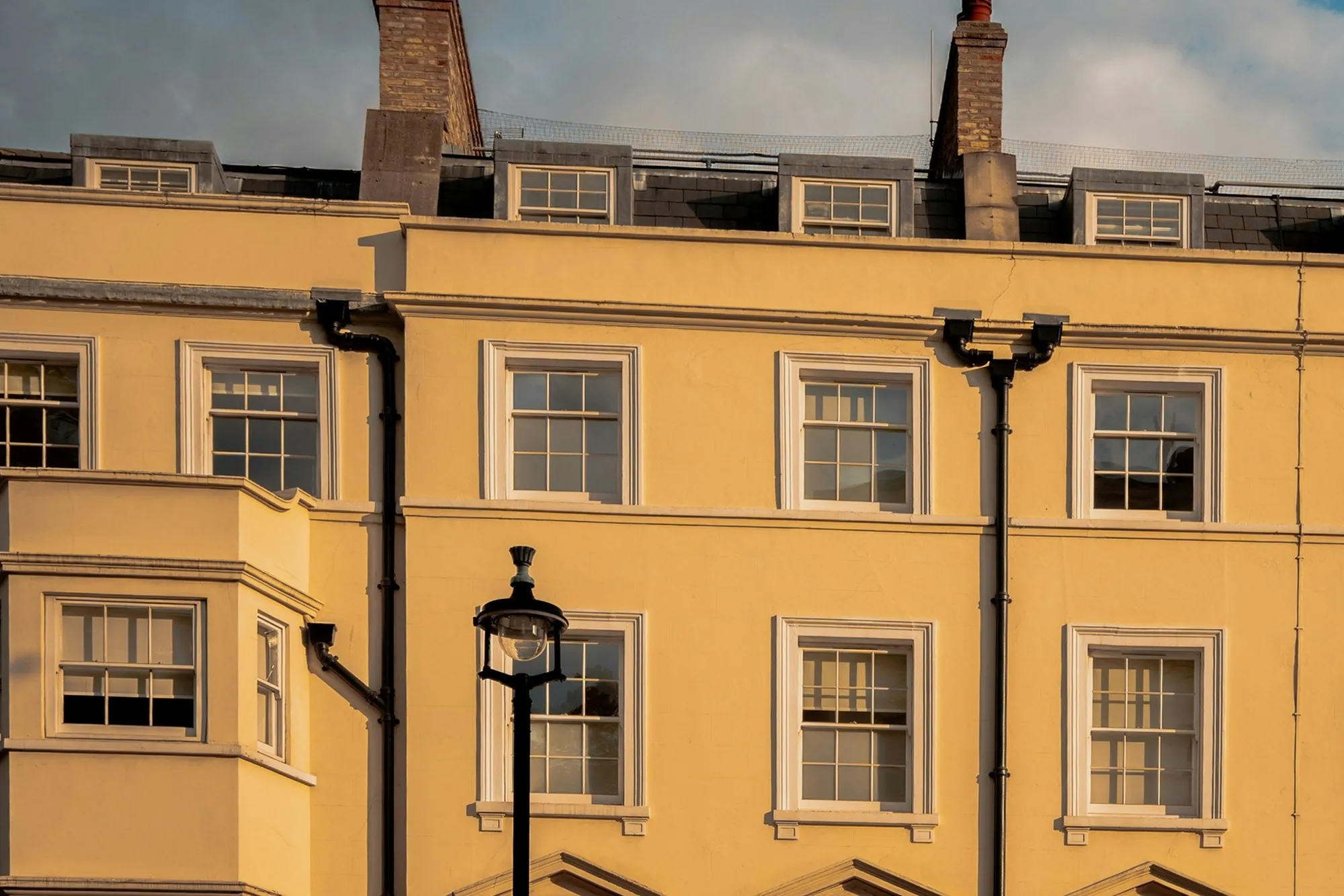 Golden-hour light on a cream stucco Georgian terrace with chimneys and dormers, London