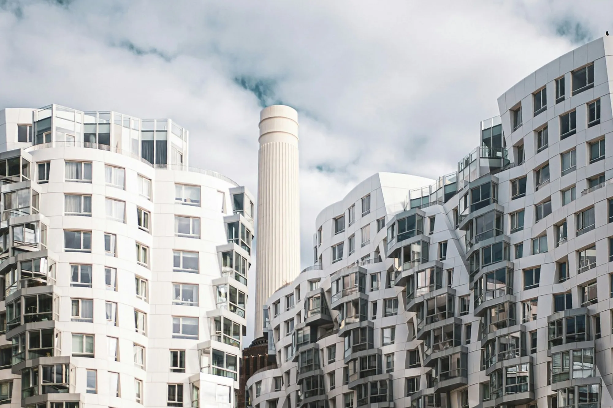 White residential towers with stepped balconies around the Battersea Power Station chimney in London
