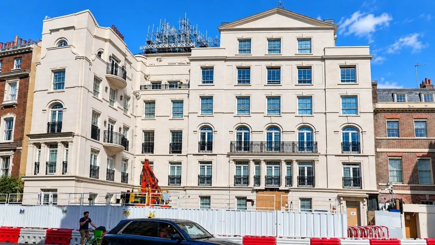 Stucco building under roof scaffold with street hoarding during works