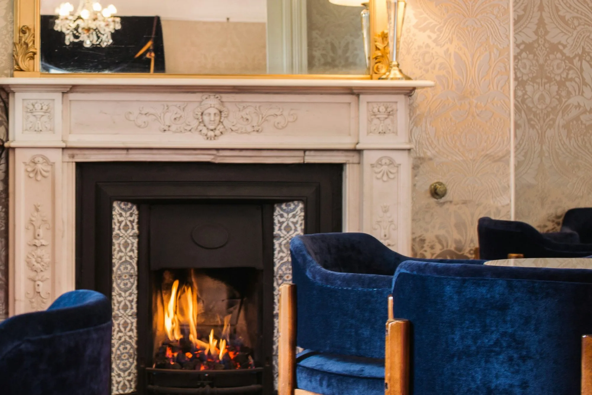 Period interior with a carved marble fireplace, gilt mirror and velvet chairs
