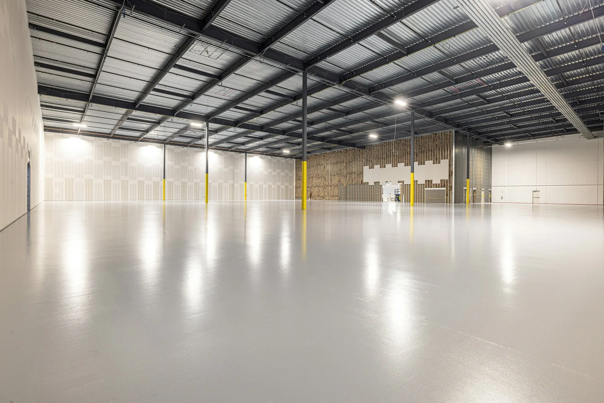 Empty clean industrial unit with a polished resin floor and a steel roof frame