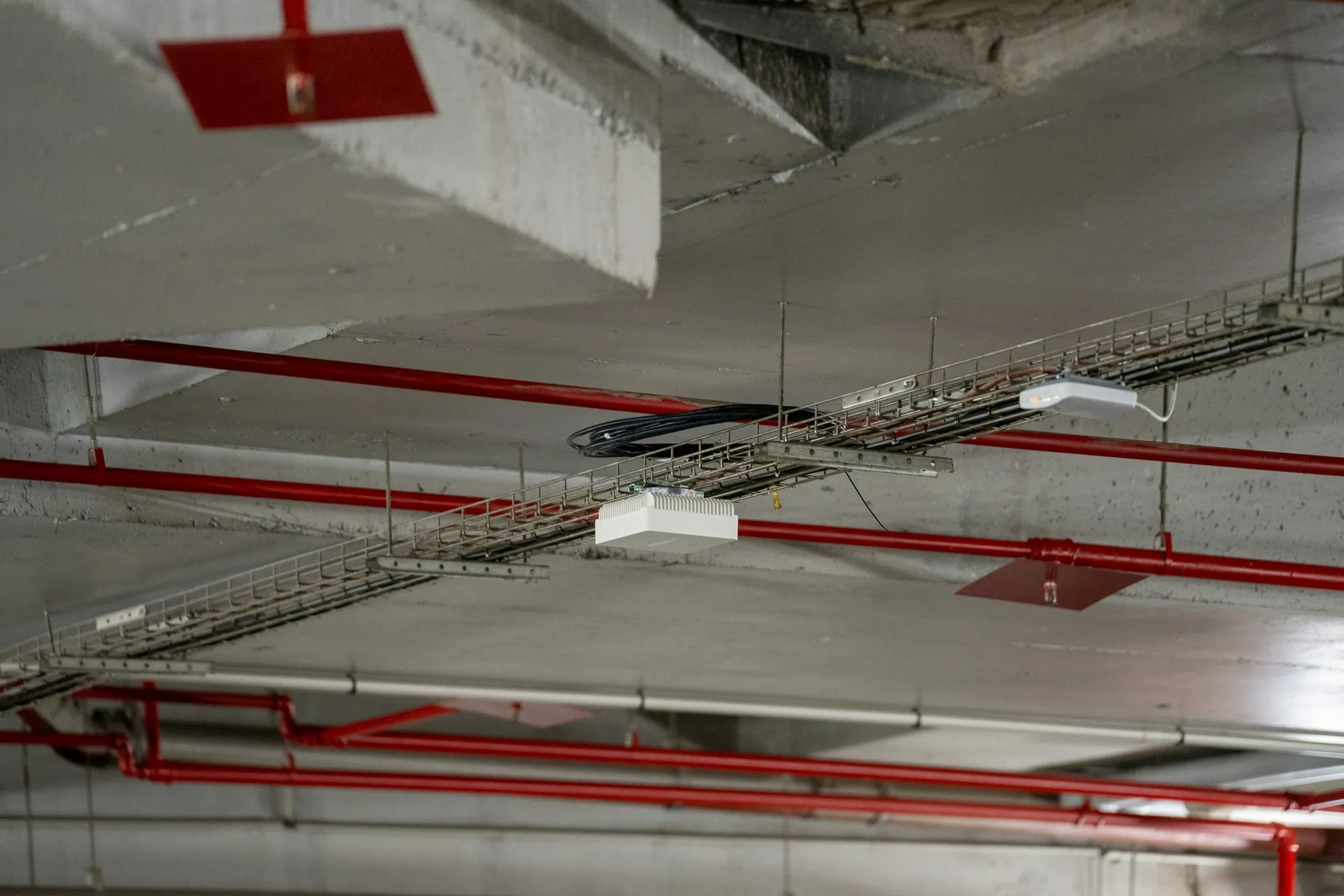 Pipes and cable trays running through a concrete ceiling soffit