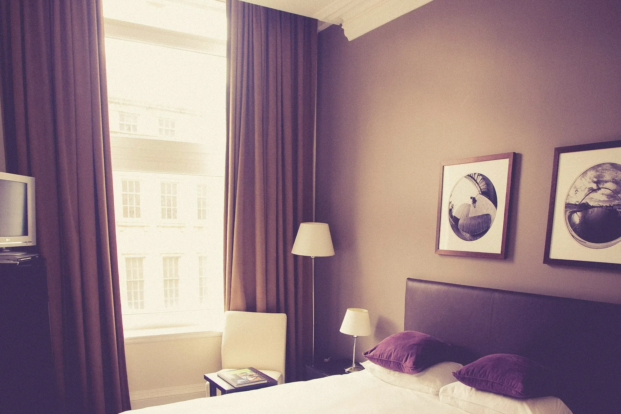 Finished luxury hotel bedroom with an upholstered headboard, bespoke joinery and lit bedside lamps