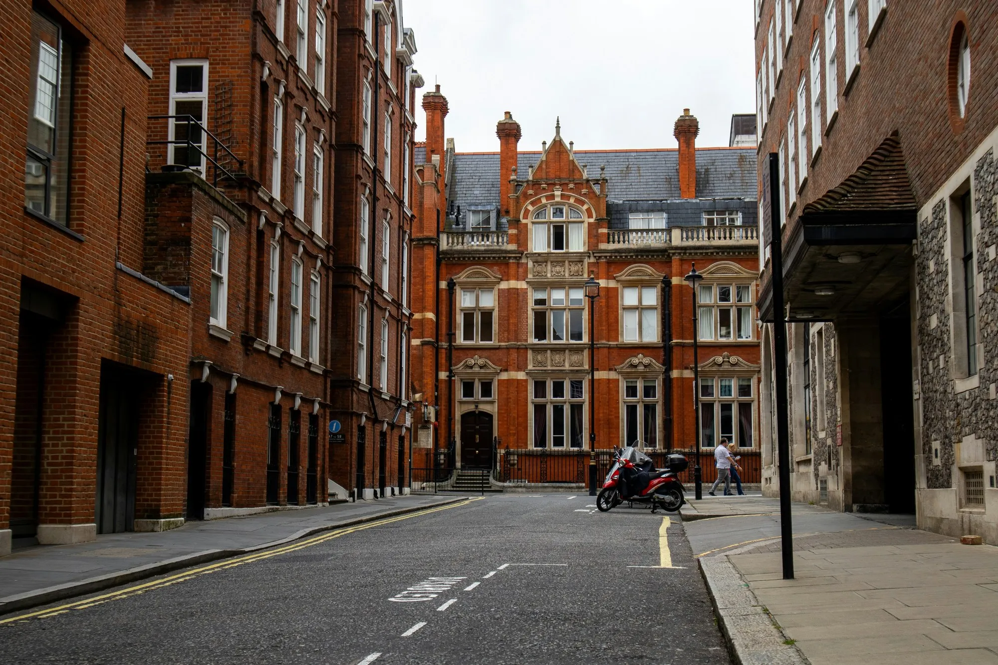 London Victorian red-brick street with ornate terracotta building at the end, daylight, empty road
