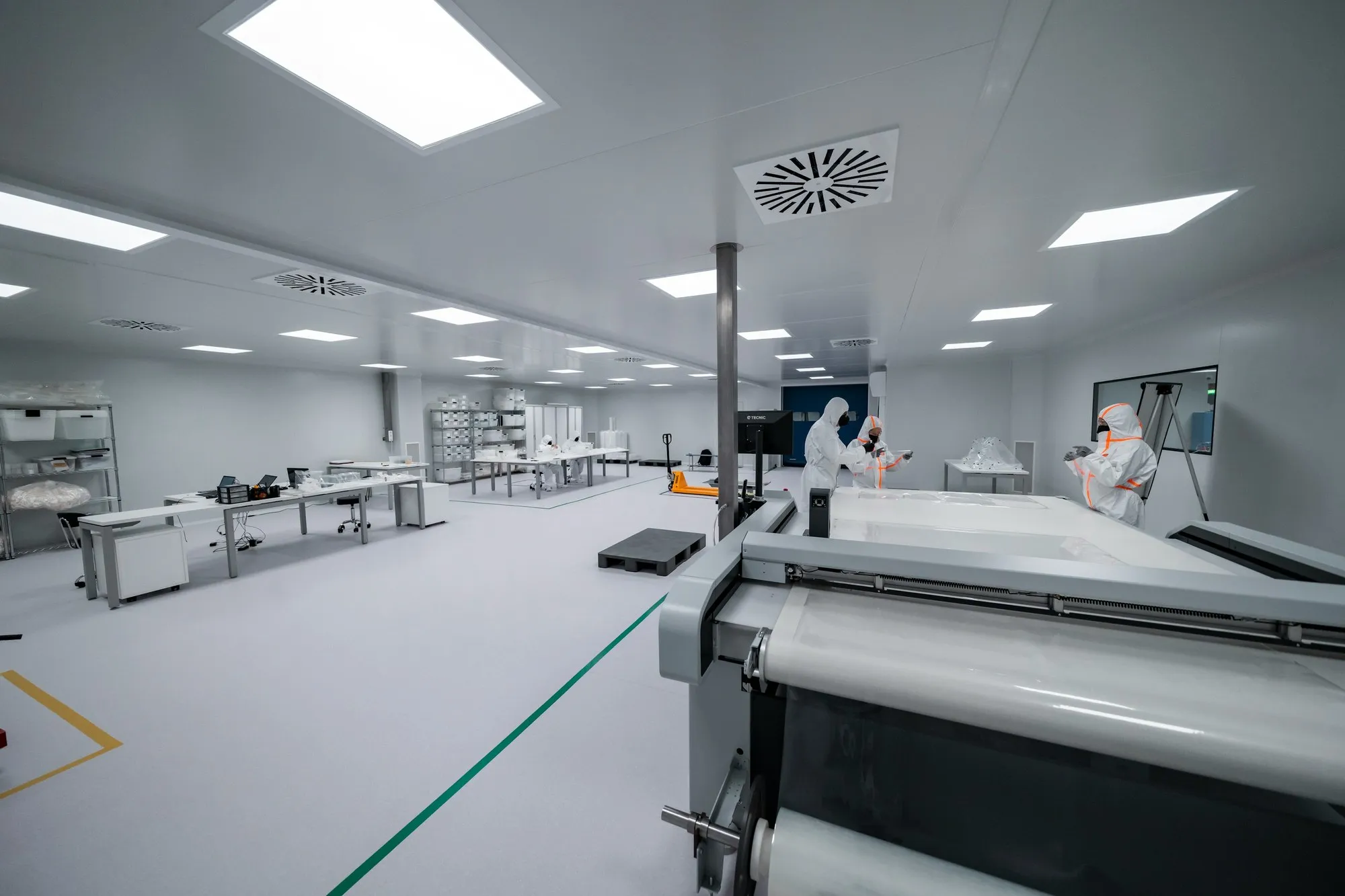 Wide cleanroom with ceiling diffuser, bench lines and gowned staff