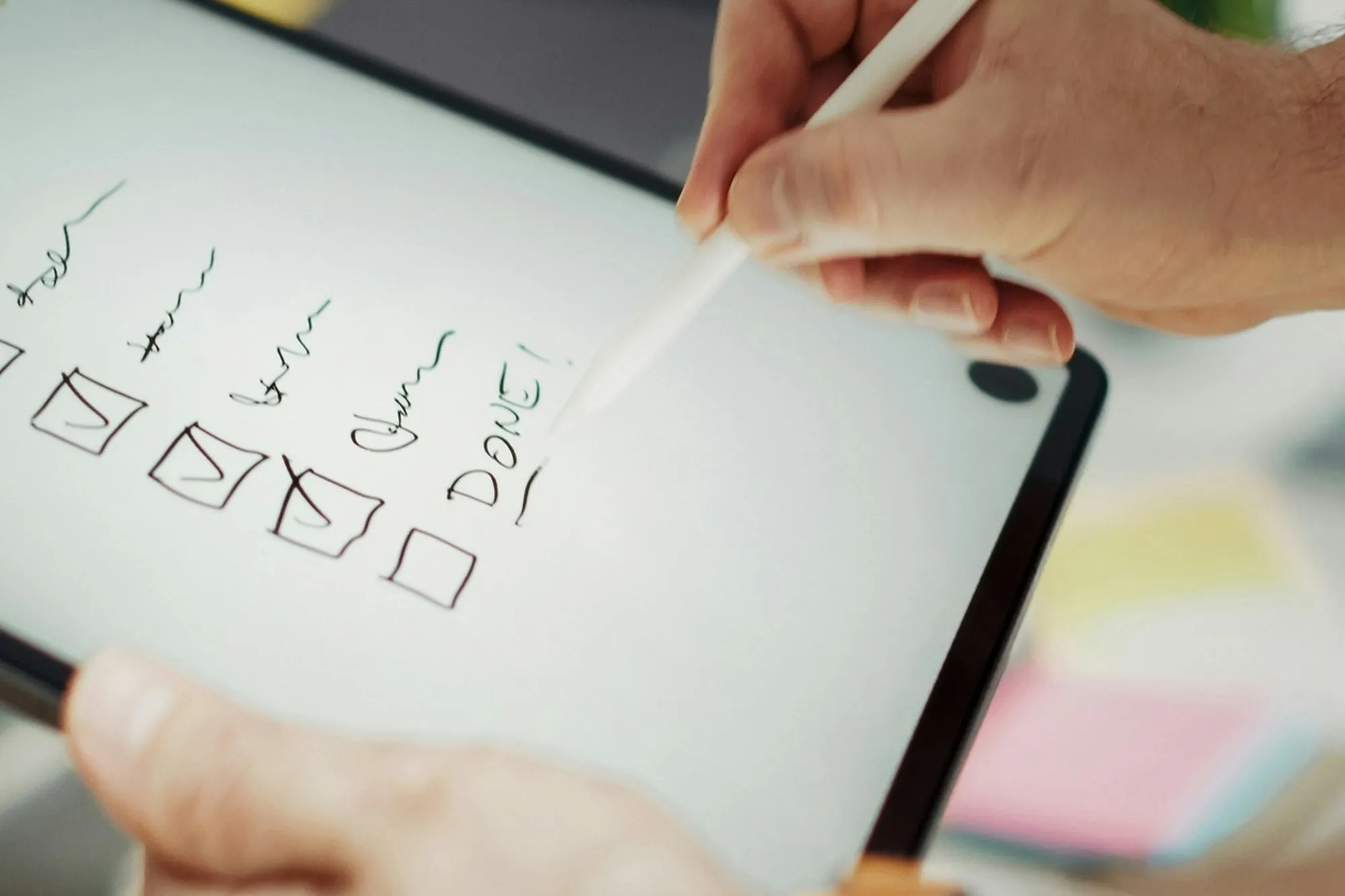 Hands ticking a checklist on a tablet with a stylus