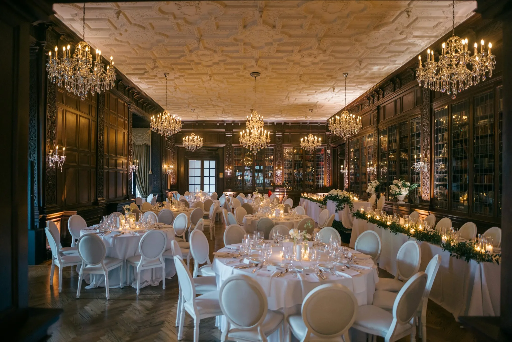 Panelled dining hall with crystal chandeliers, white-clothed tables and a decorative plaster ceiling