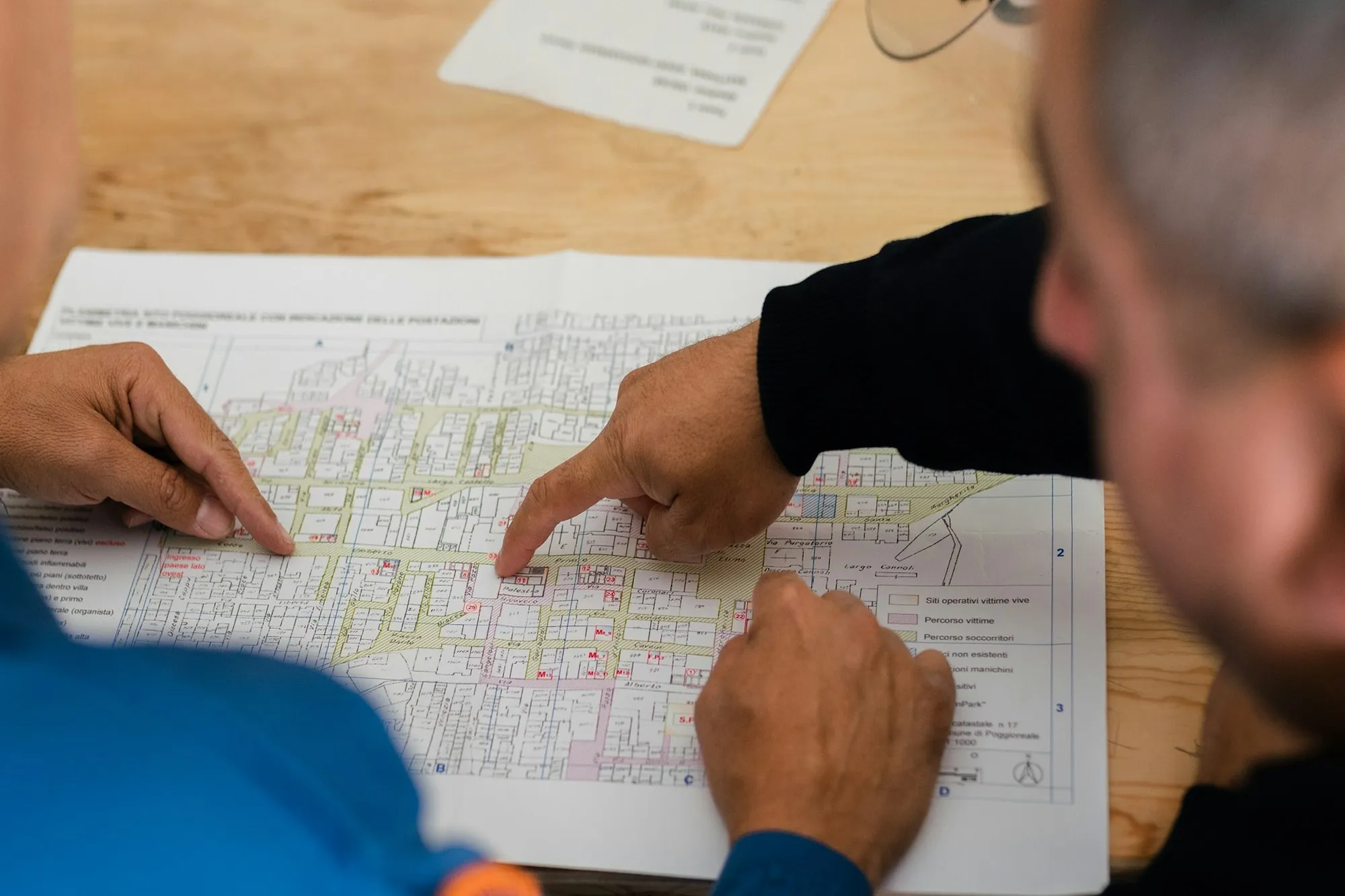 Two engineers pointing at a marked-up site plan on the table