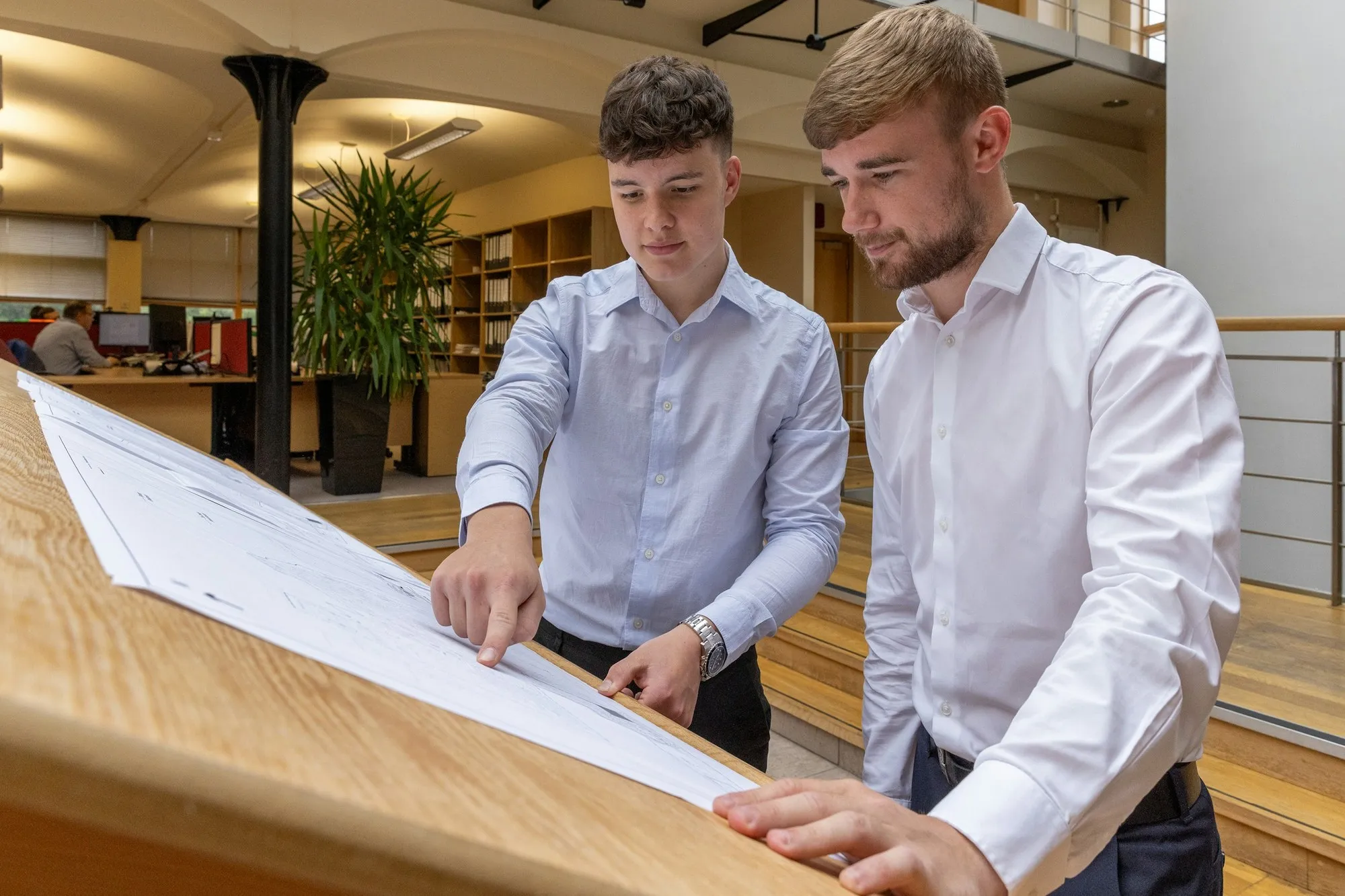 Two colleagues reviewing tender drawings at a desk