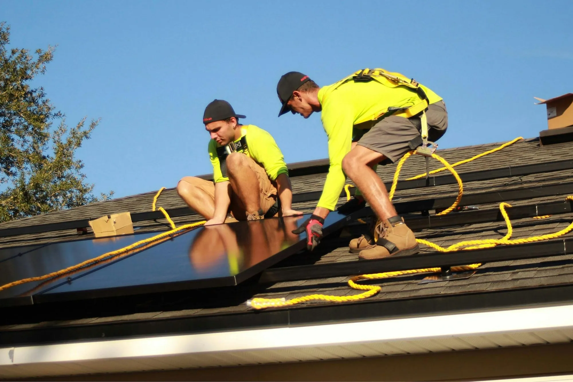 Installers fitting solar panels on a pitched house roof