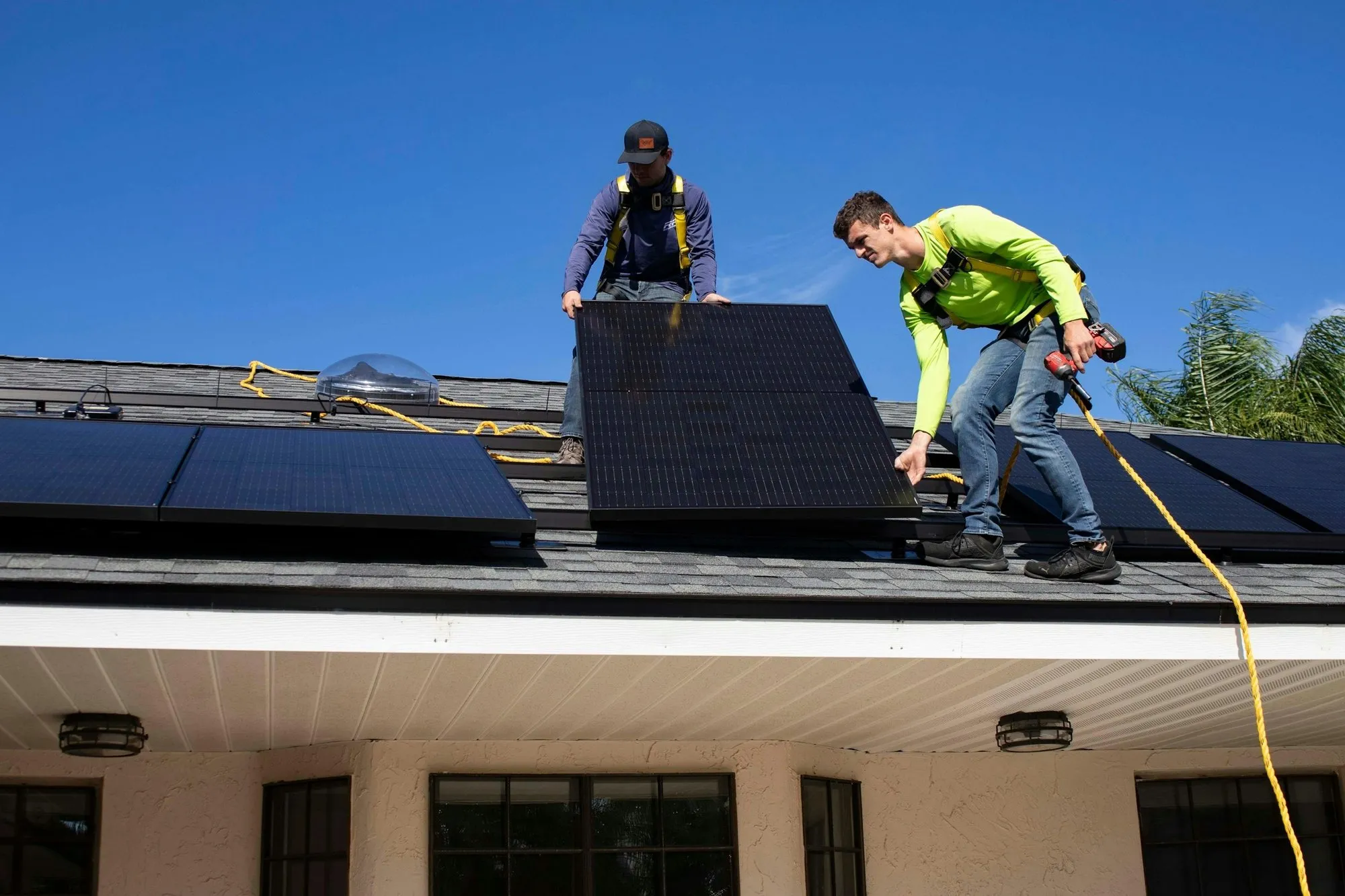 Installer placing a black solar panel on a house roof