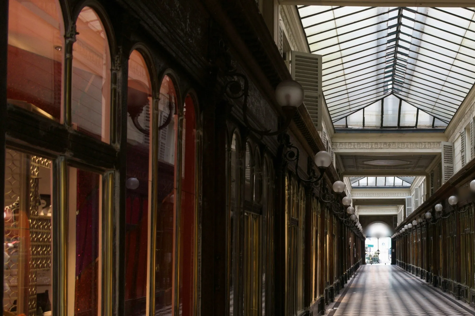 Paris covered arcade with lit arched shop windows, globe lamps and chequered floor