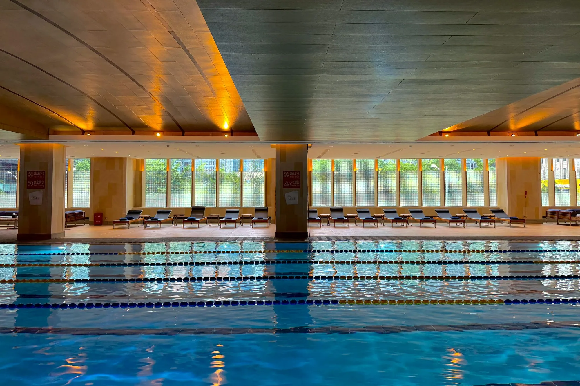 Empty indoor swimming pool with lane ropes under a timber ceiling