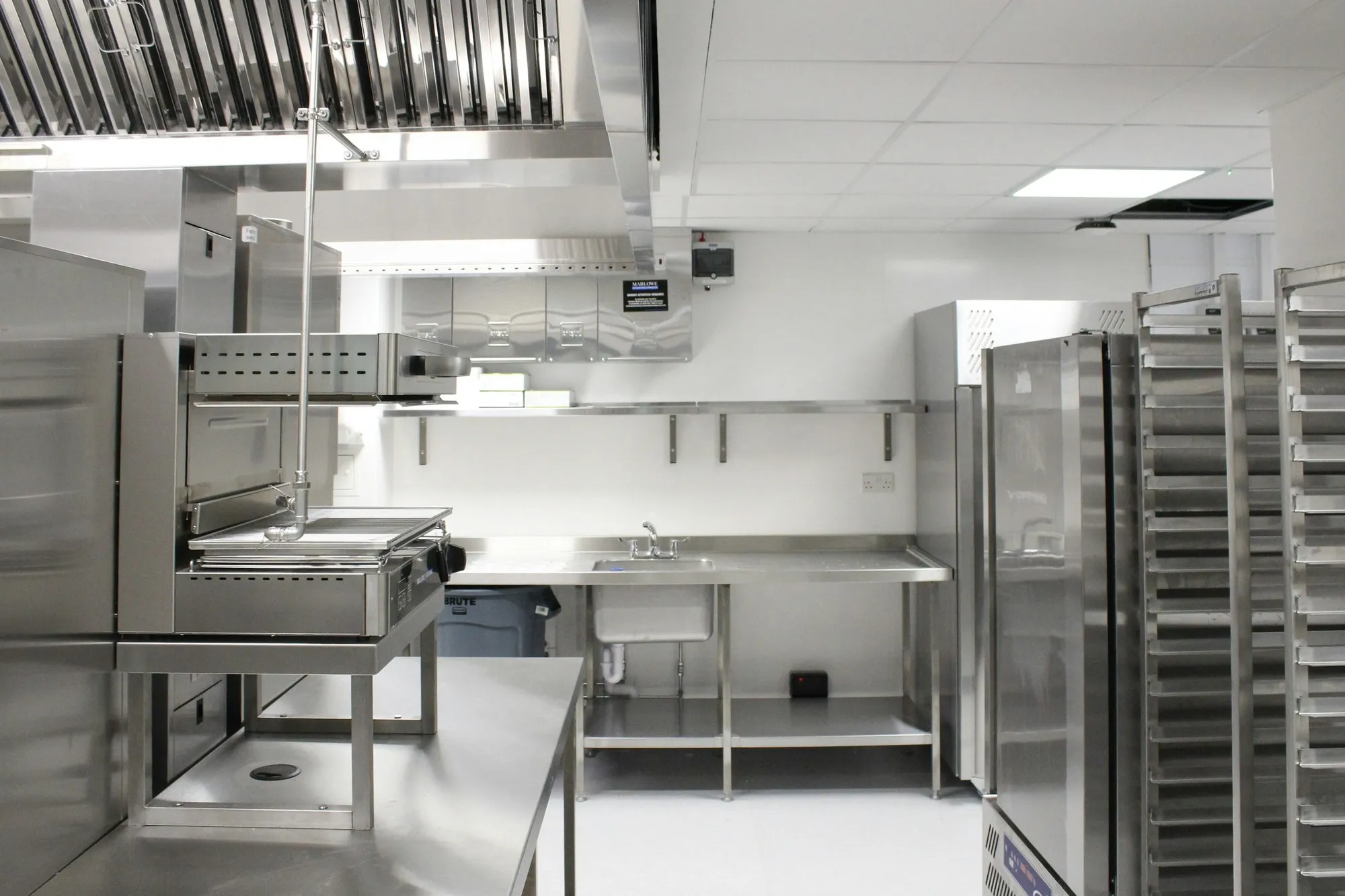 Empty commercial kitchen with stainless steel cooking line and racking