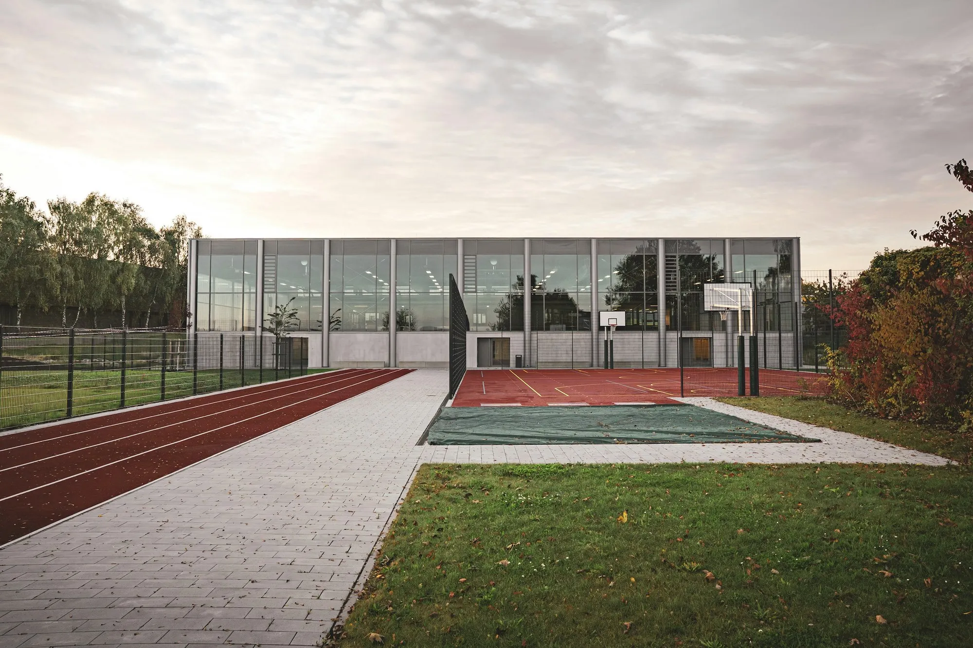 Multi-use games court with fencing, running track and sports hall behind