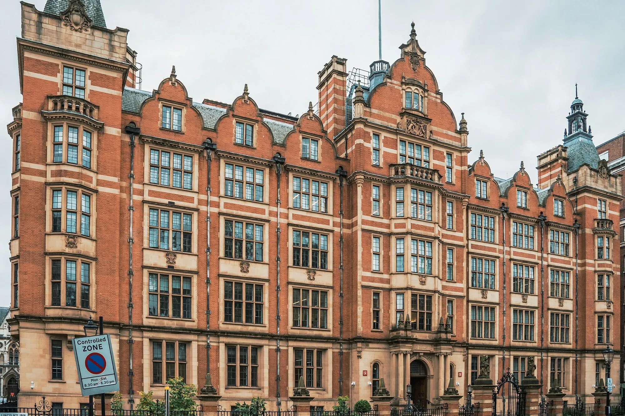 Red brick and terracotta Victorian building with a gabled roofline and tall windows on a London street