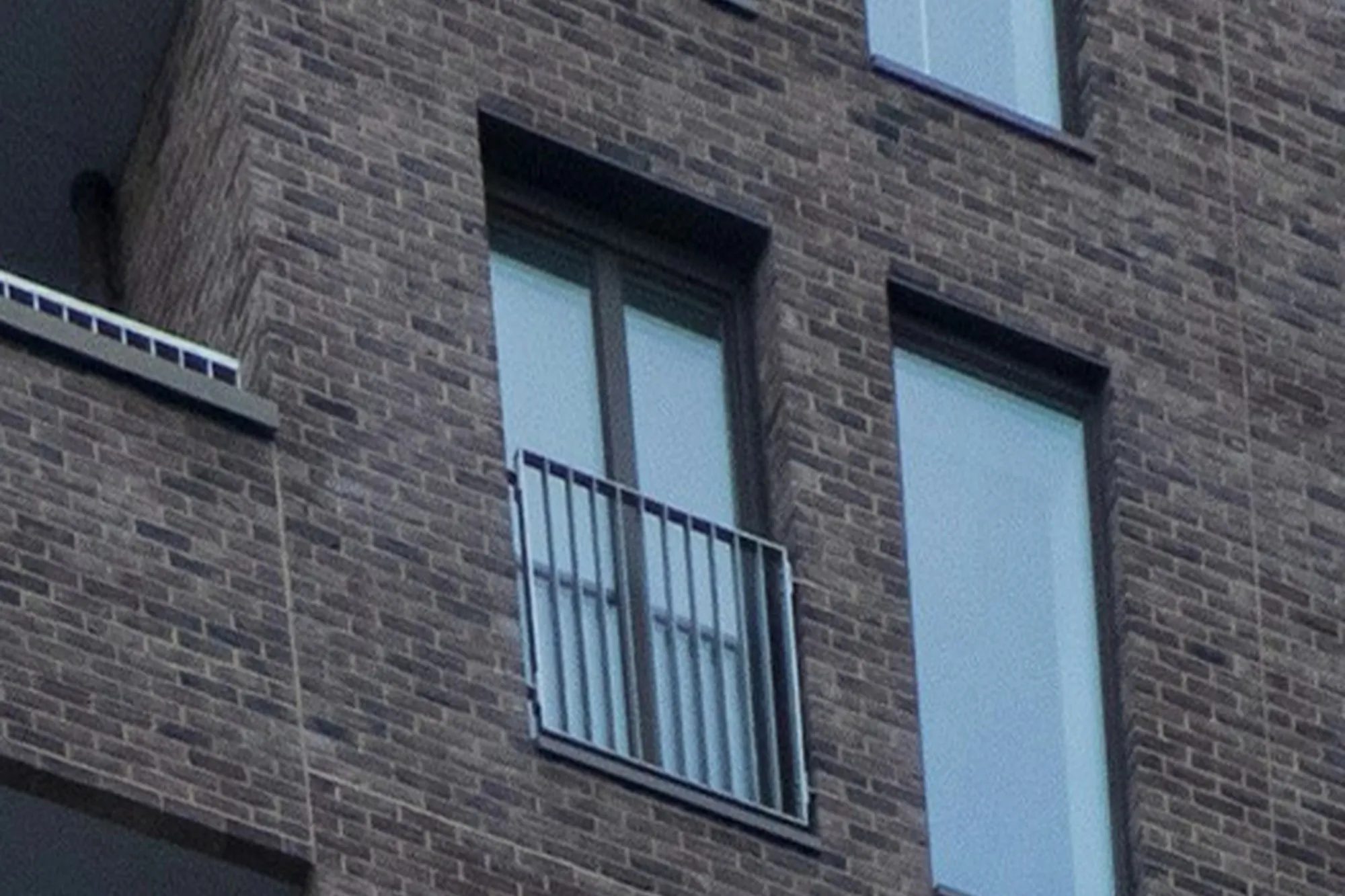 Brick apartment facade with new windows and a Juliet balcony door