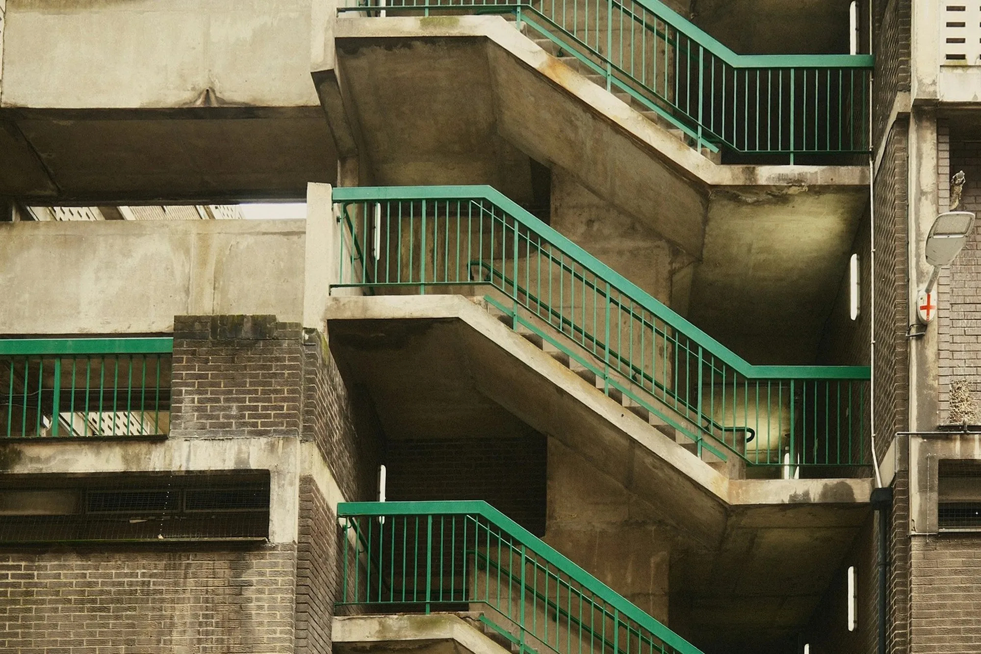Concrete deck-access stairs and walkways with green railings on a London block