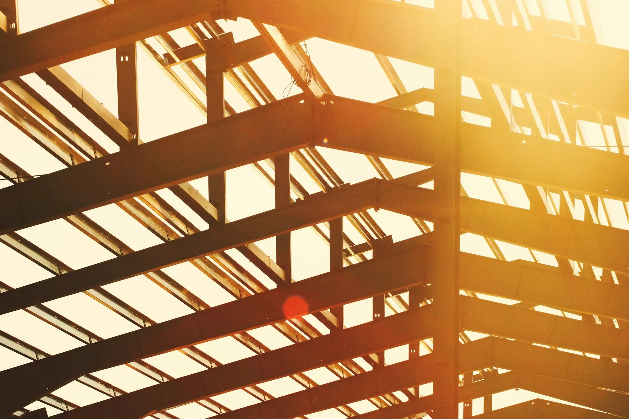 Exposed steel portal frame rafters and columns against bright sky