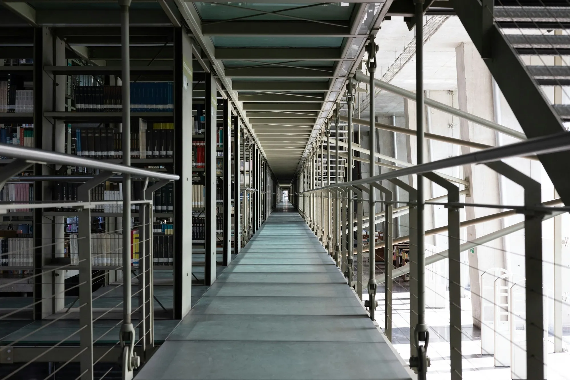 Steel gallery walkway with railings running between tall shelving