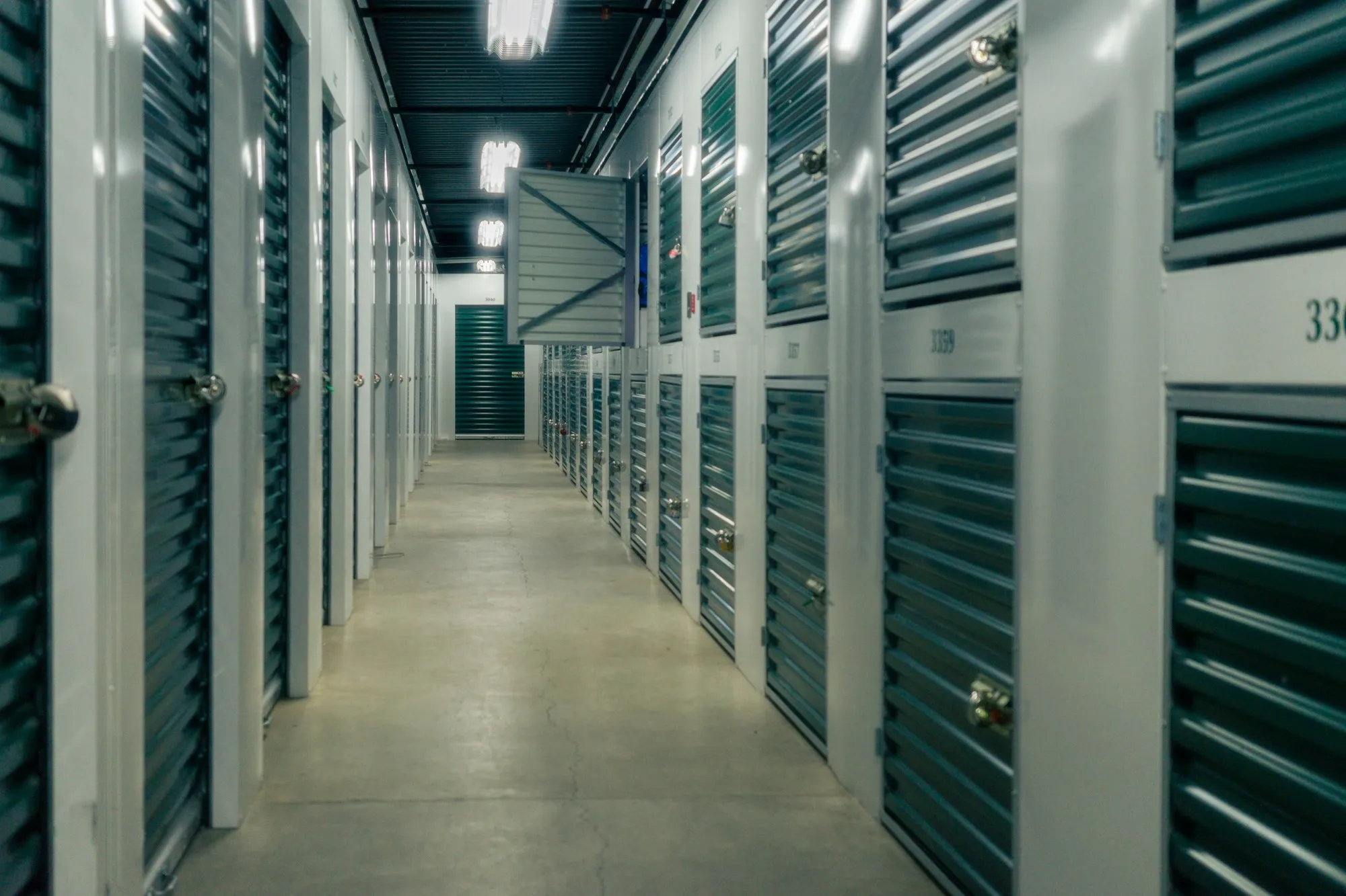 Storage corridor with teal roll-up unit doors on both sides