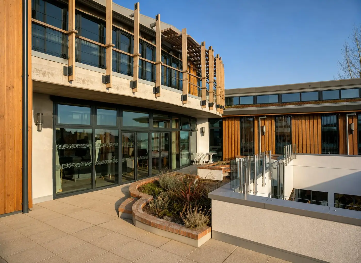 Completed Macmillan Cancer Care Centre in London, with timber-clad facade and landscaped terrace