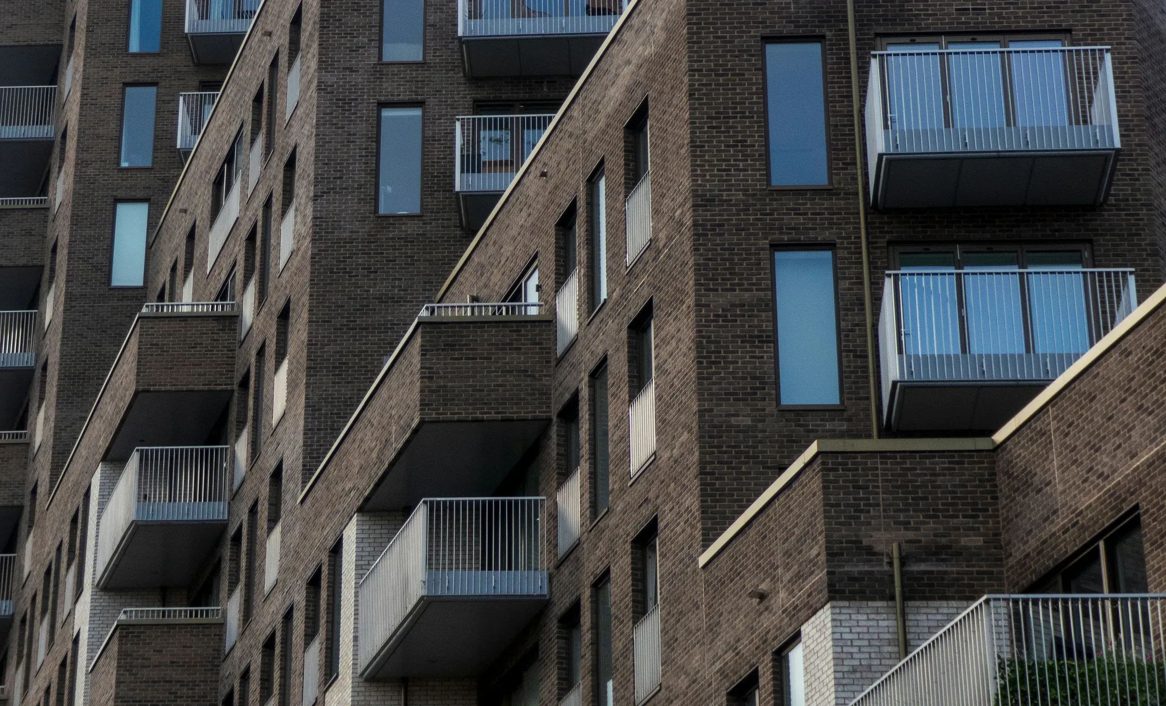 Dark brick apartment building with glazed balconies at Phoenix Place, London