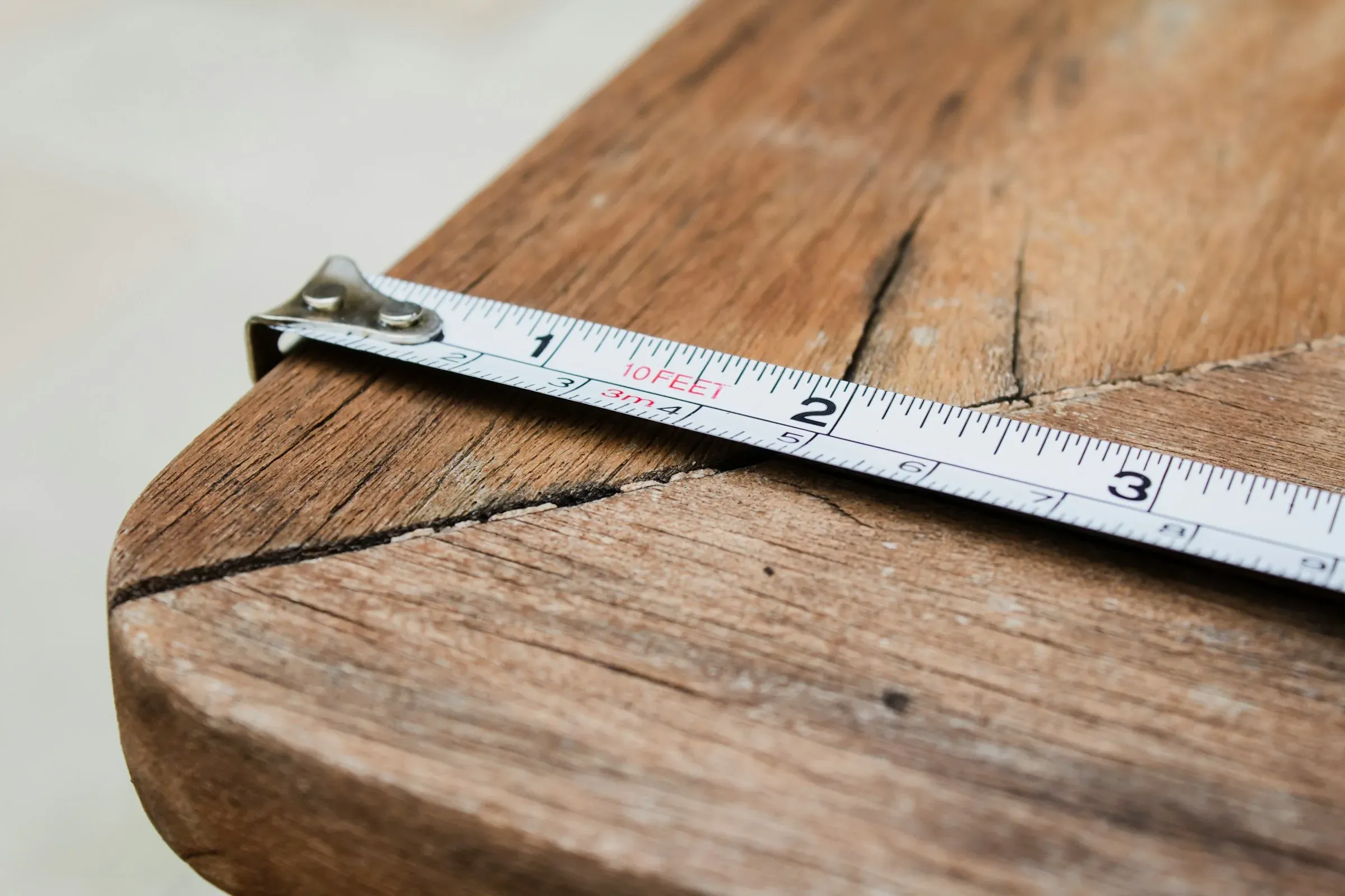 Tape measure laid across the worn edge of a timber table top