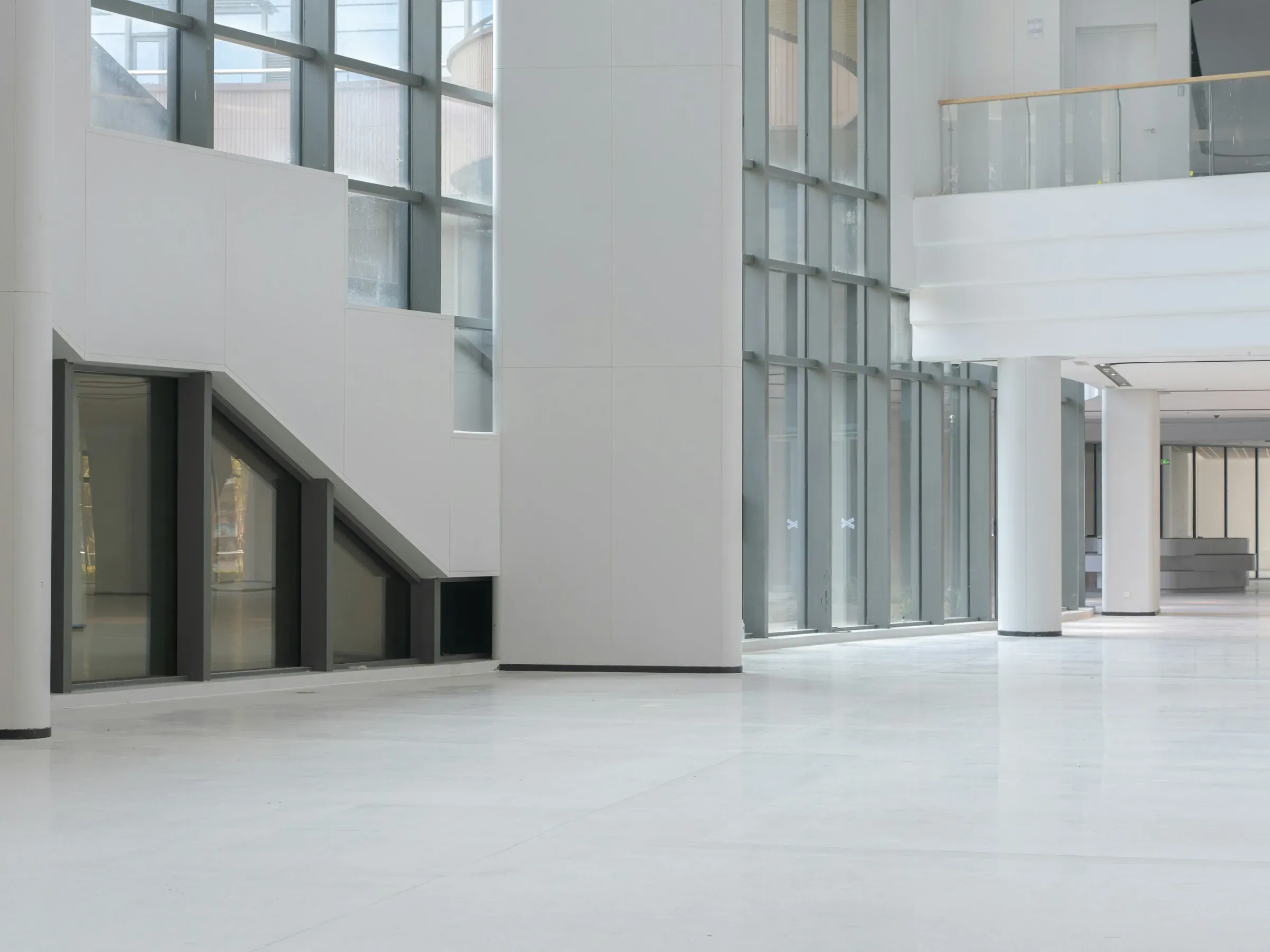 Empty white commercial floor with a bare polished floor, columns and floor-to-ceiling glazing