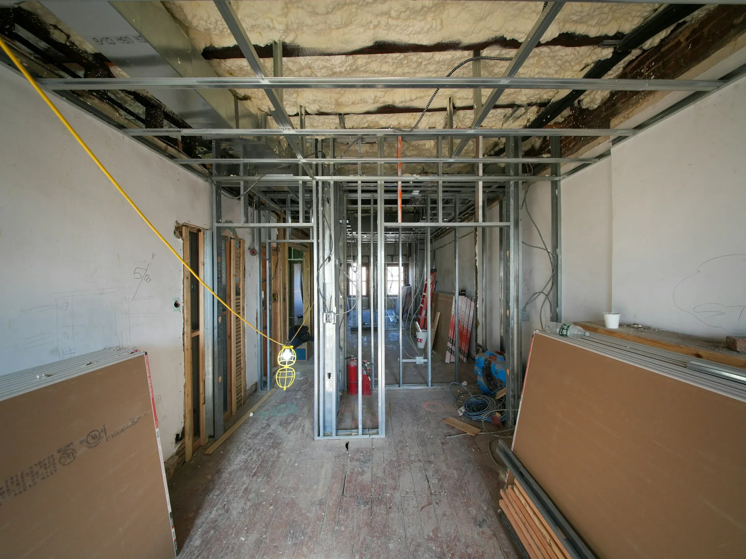 Stripped-out floor with new metal stud partitions, exposed ceiling insulation and plasterboard sheets ready to fit
