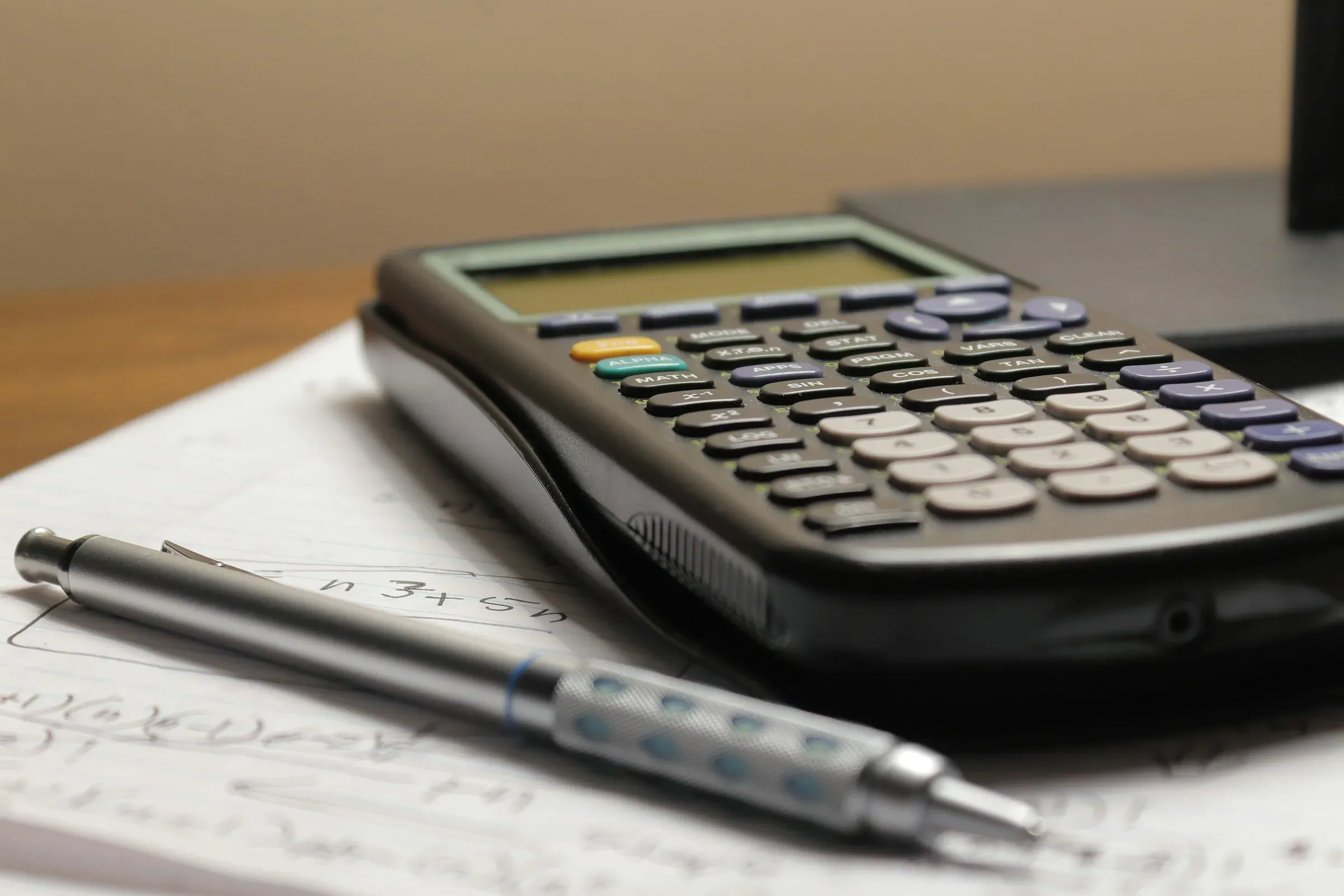 Calculator and pencil resting on a sheet of handwritten calculations
