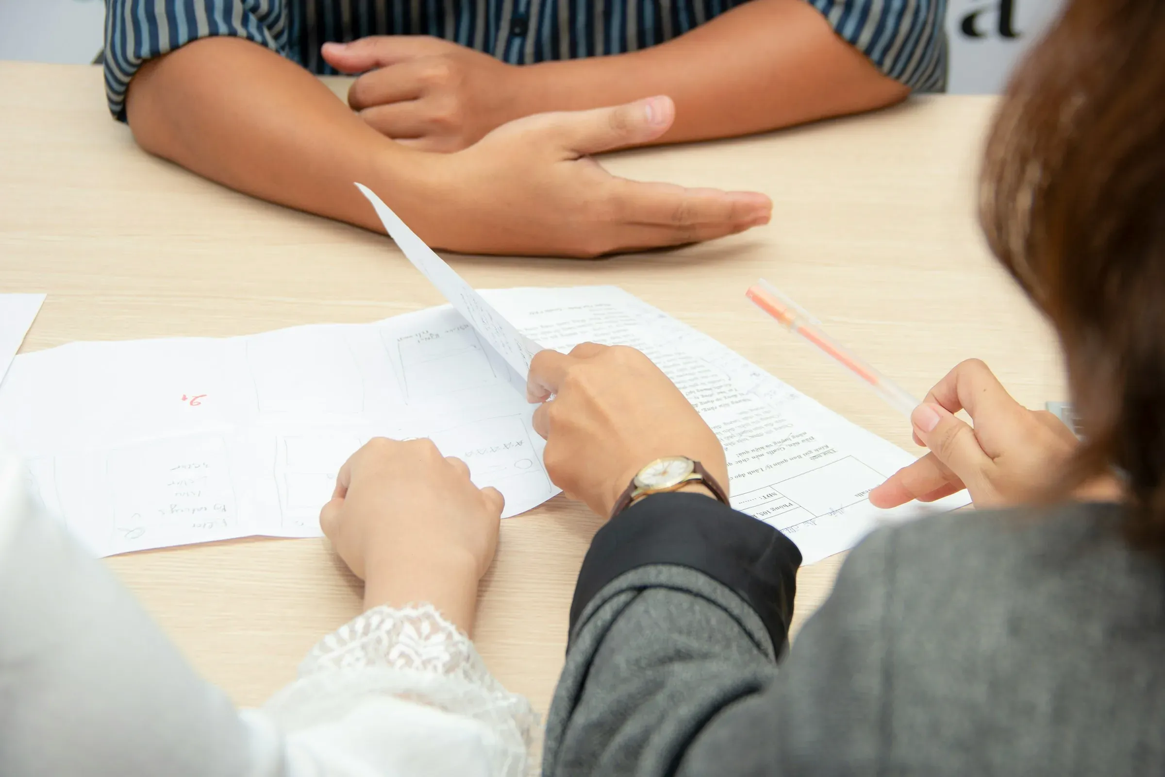 Two people reviewing papers across a meeting table
