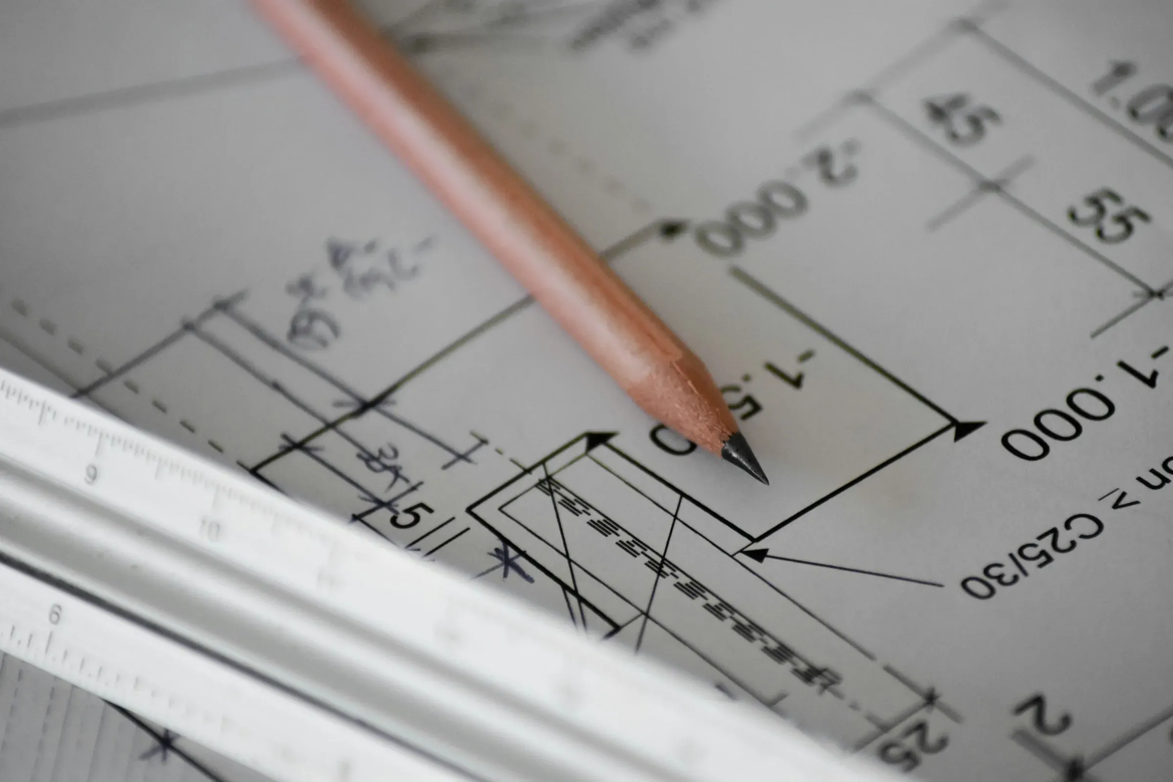 Pencil resting on a dimensioned technical drawing beside a scale ruler