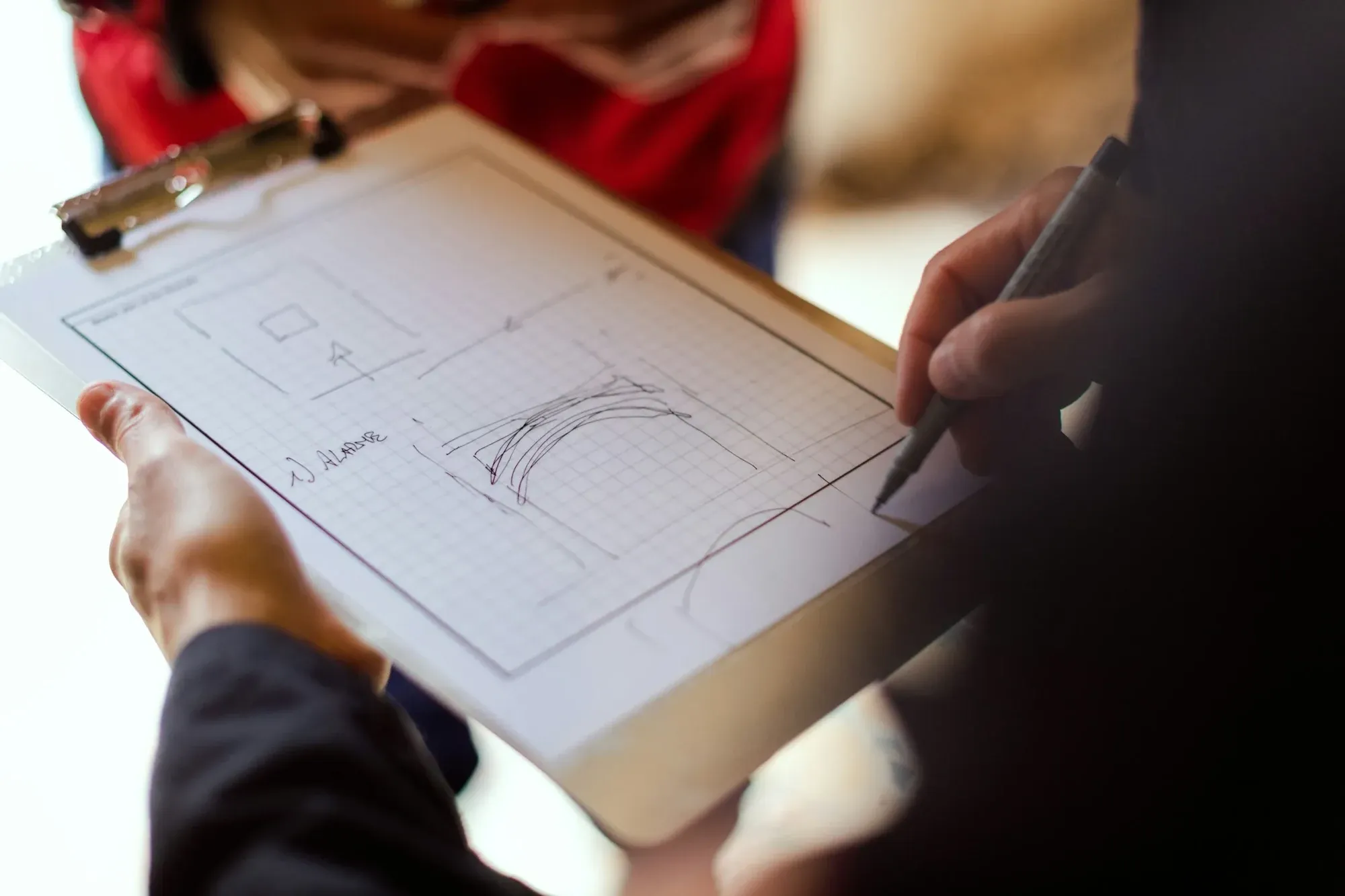 Hand sketching a layout on a clipboard during a site briefing