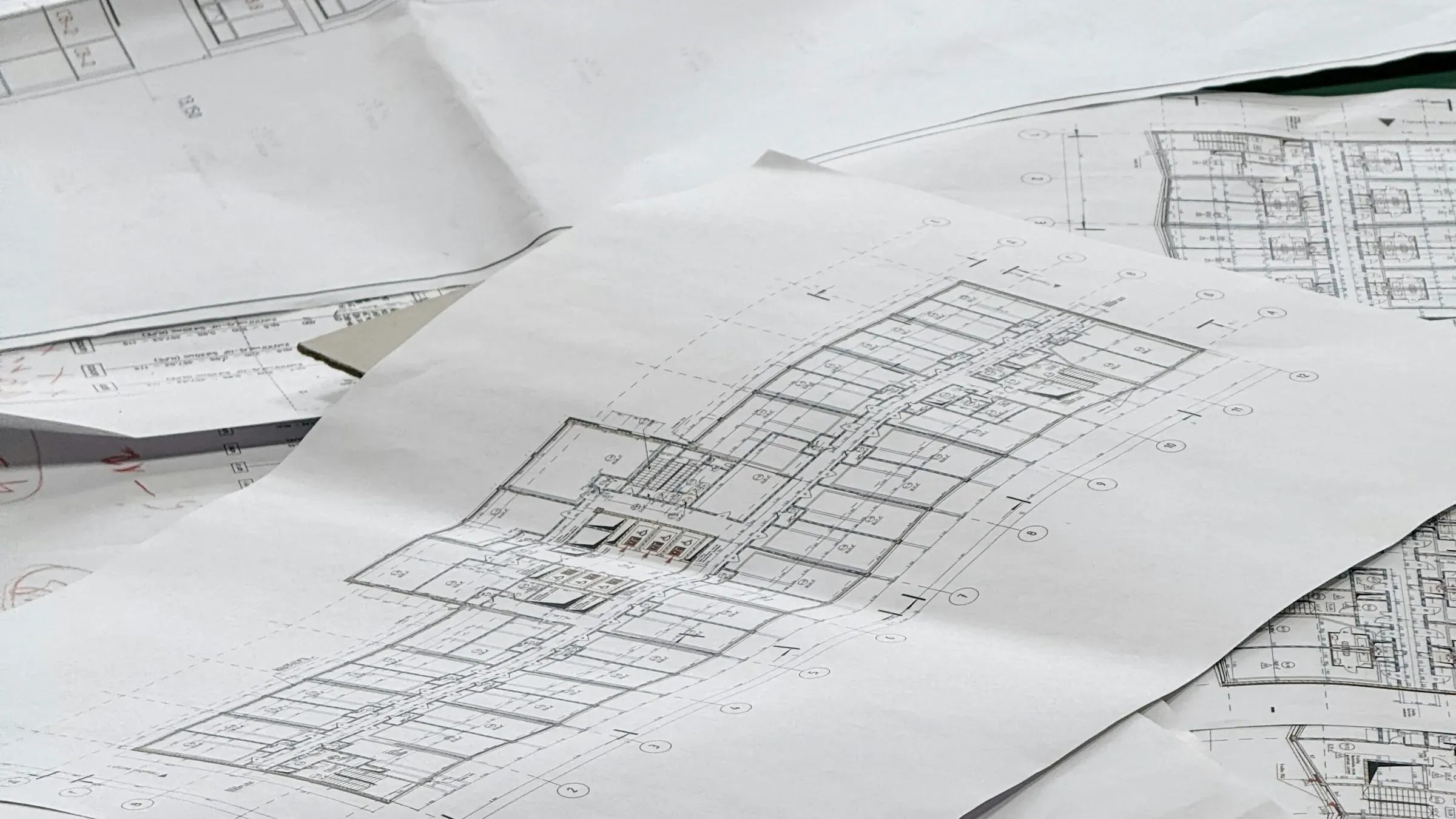 Printed architectural floor plans of an apartment block spread across a table