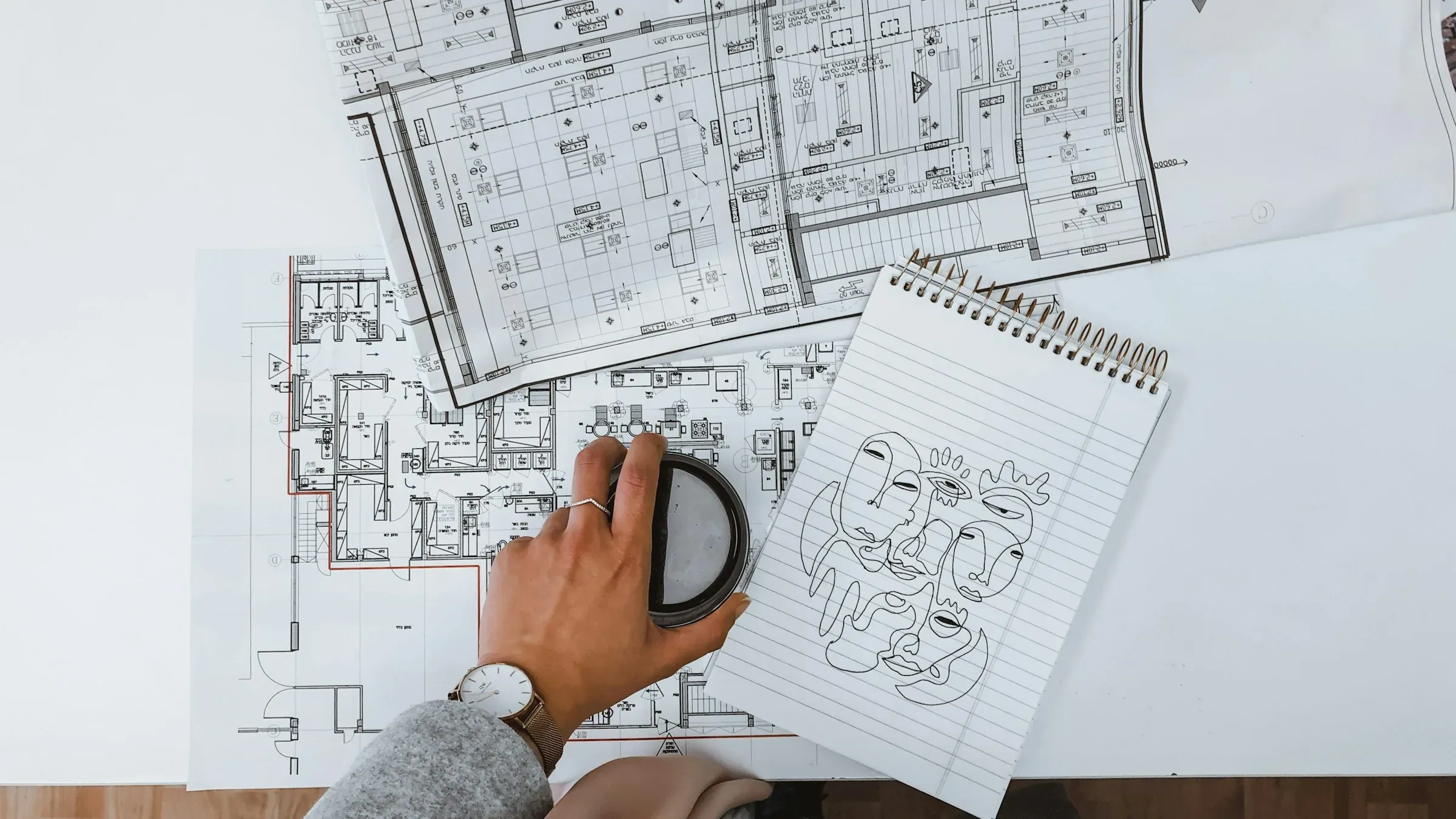 Hand holding a magnifying glass over printed floor plans