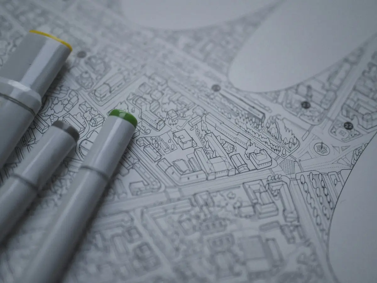 Three grey sketch markers resting on a finely drawn city masterplan in black line