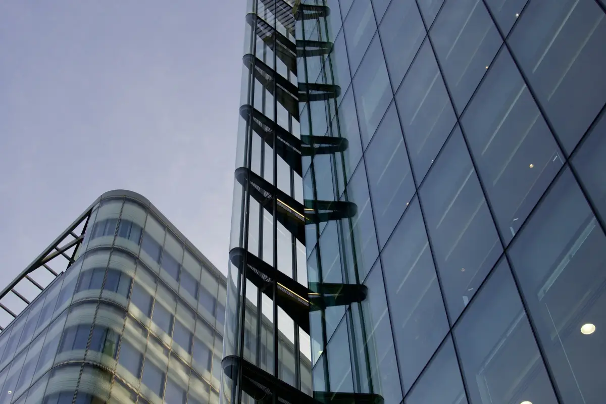 Full-height glazed office facade in London with a glass-enclosed staircase against a dusk sky