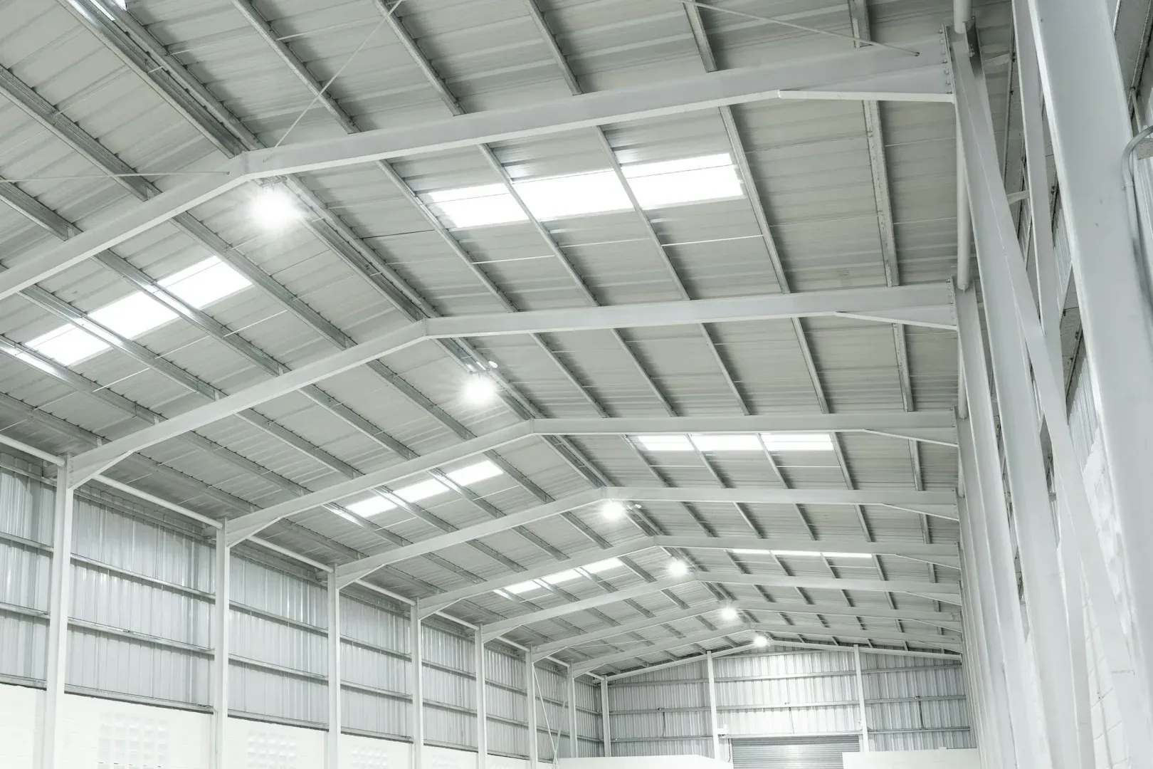 White steel roof frame of an industrial unit with rooflights and LED high-bay lights