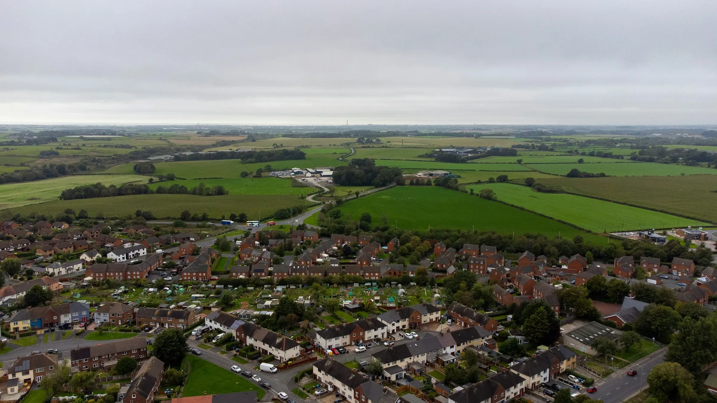 Aerial view of a housing estate bordering green fields on the edge of an English town