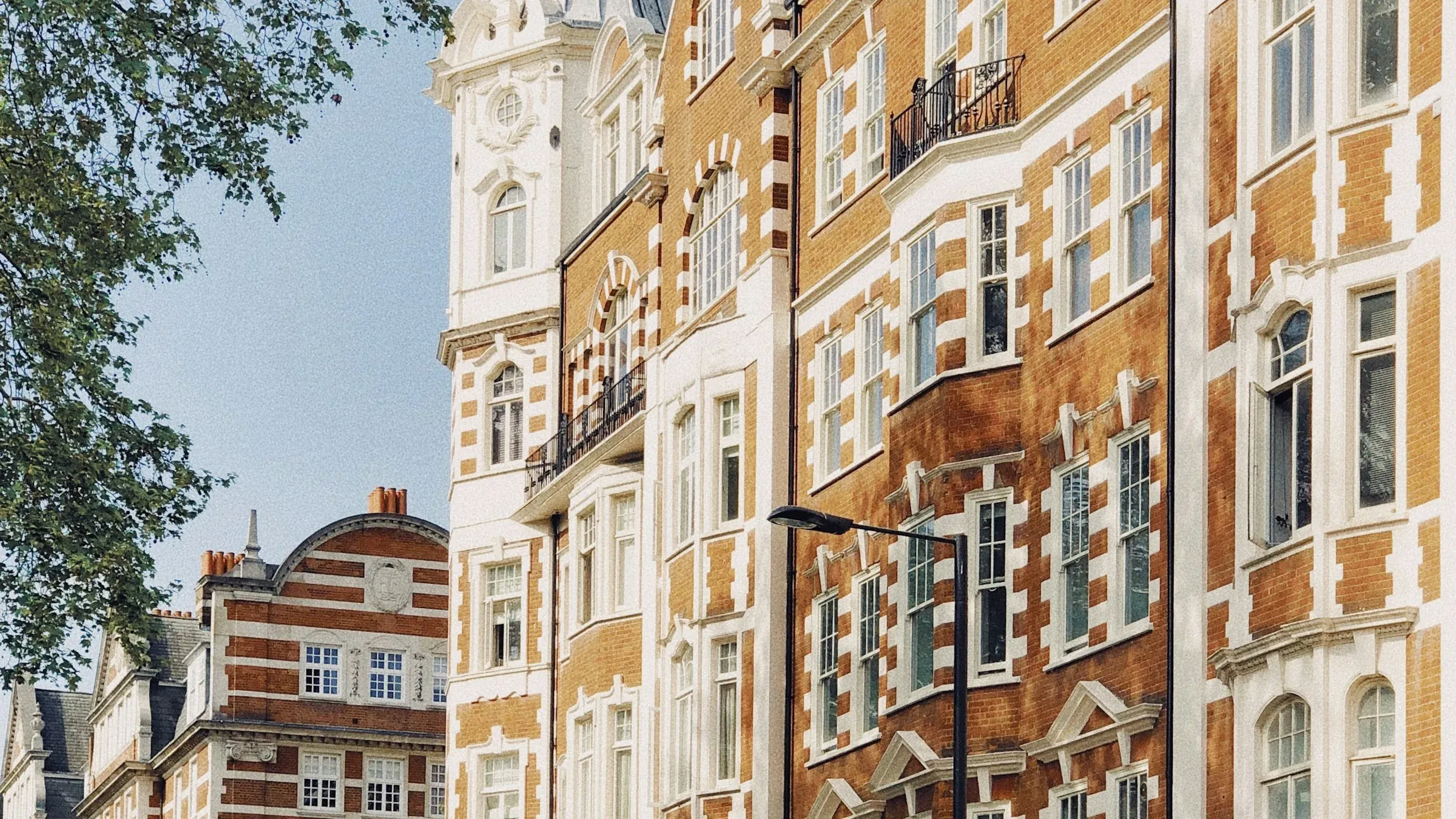 Red brick and white stone Victorian mansion block with a corner turret in St John's Wood, London